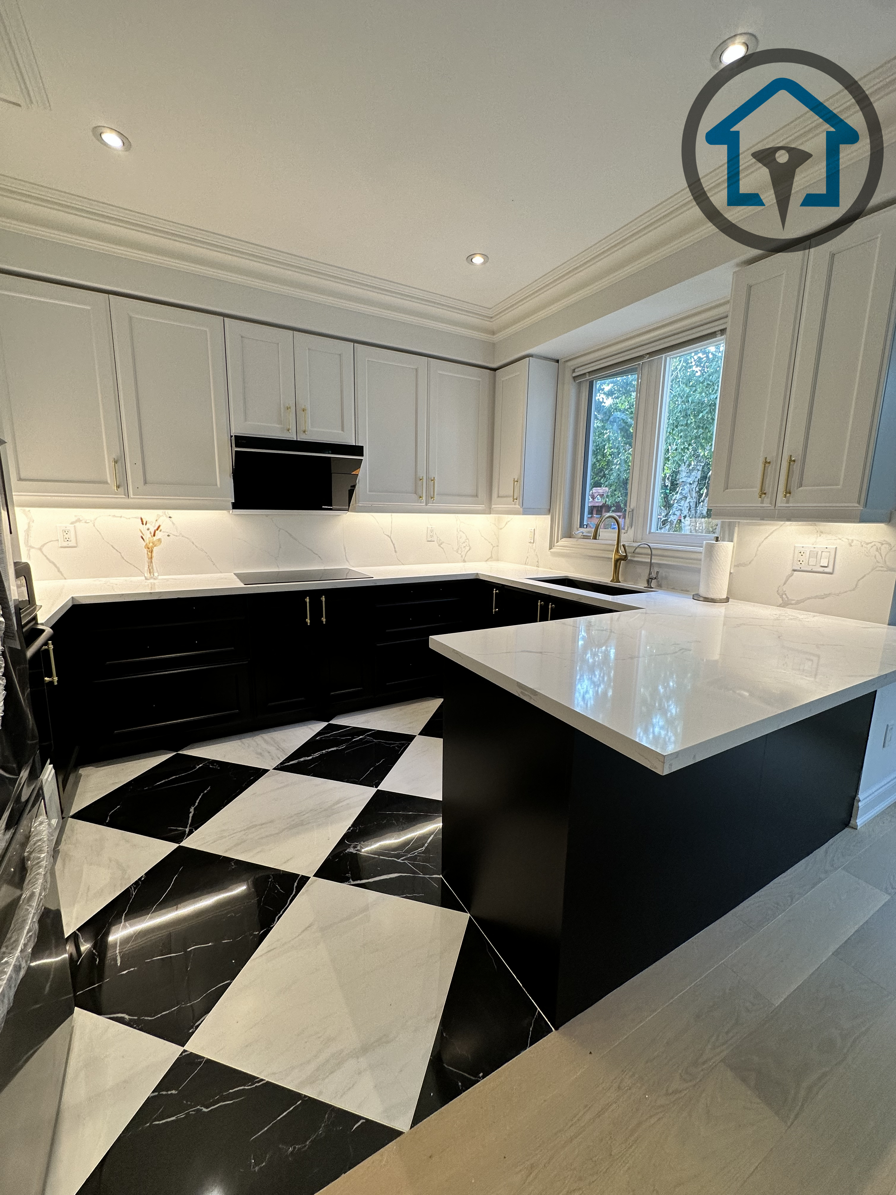Modern kitchen completed as part of a North York interior renovation, featuring custom shaker-style cabinetry, a large quartz island, and bold black-and-white geometric tile flooring. Integrated lighting, clean millwork lines, and a functional layout create a refined yet practical cooking space, delivered by a professional Toronto renovation company specializing in full interior renovations.