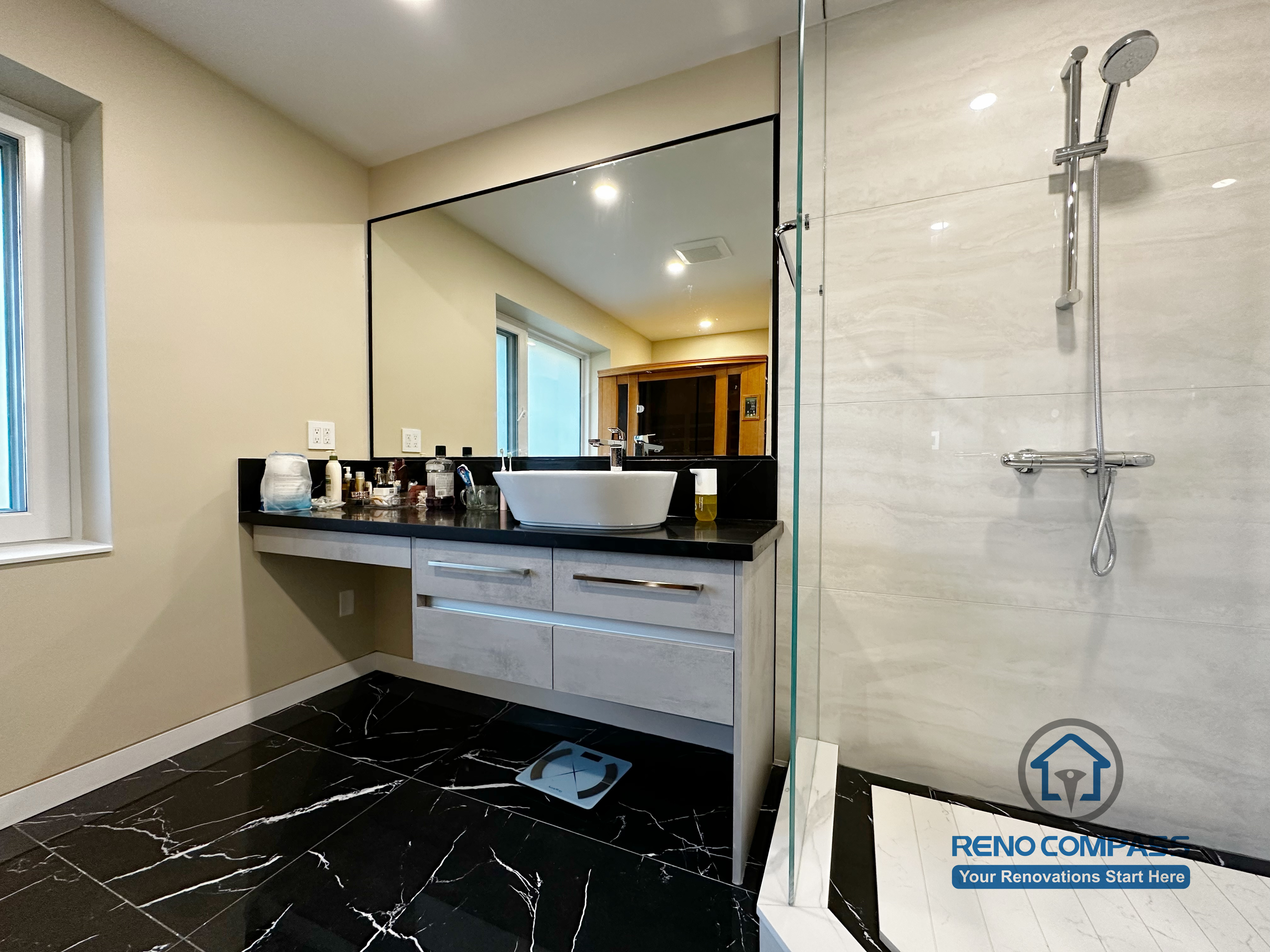 Bathroom vanity completed as part of a North York interior renovation. This design features a custom floating vanity, vessel sink, black countertop, and large wall mirror, paired with marble-look flooring and a glass shower enclosure. Built with a focus on durability, clean detailing, and daily usability by a professional Toronto renovation company.