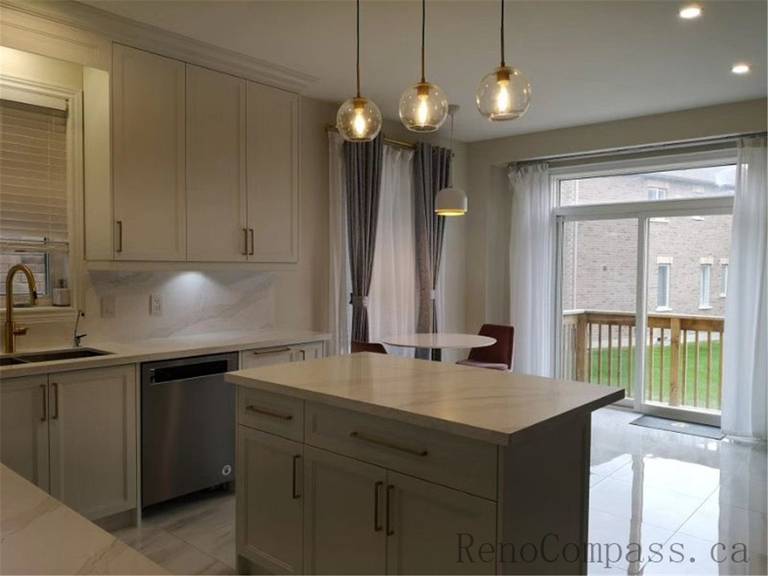 This Aurora kitchen renovation showcases a bright open-concept design featuring custom white shaker cabinets, quartz countertops, and a functional center island. Elegant pendant lighting, marble-style flooring, and brushed gold fixtures add warmth and sophistication to the modern space. Completed by a professional Toronto renovation company focused on quality craftsmanship, efficient layout planning, and timeless interior design.