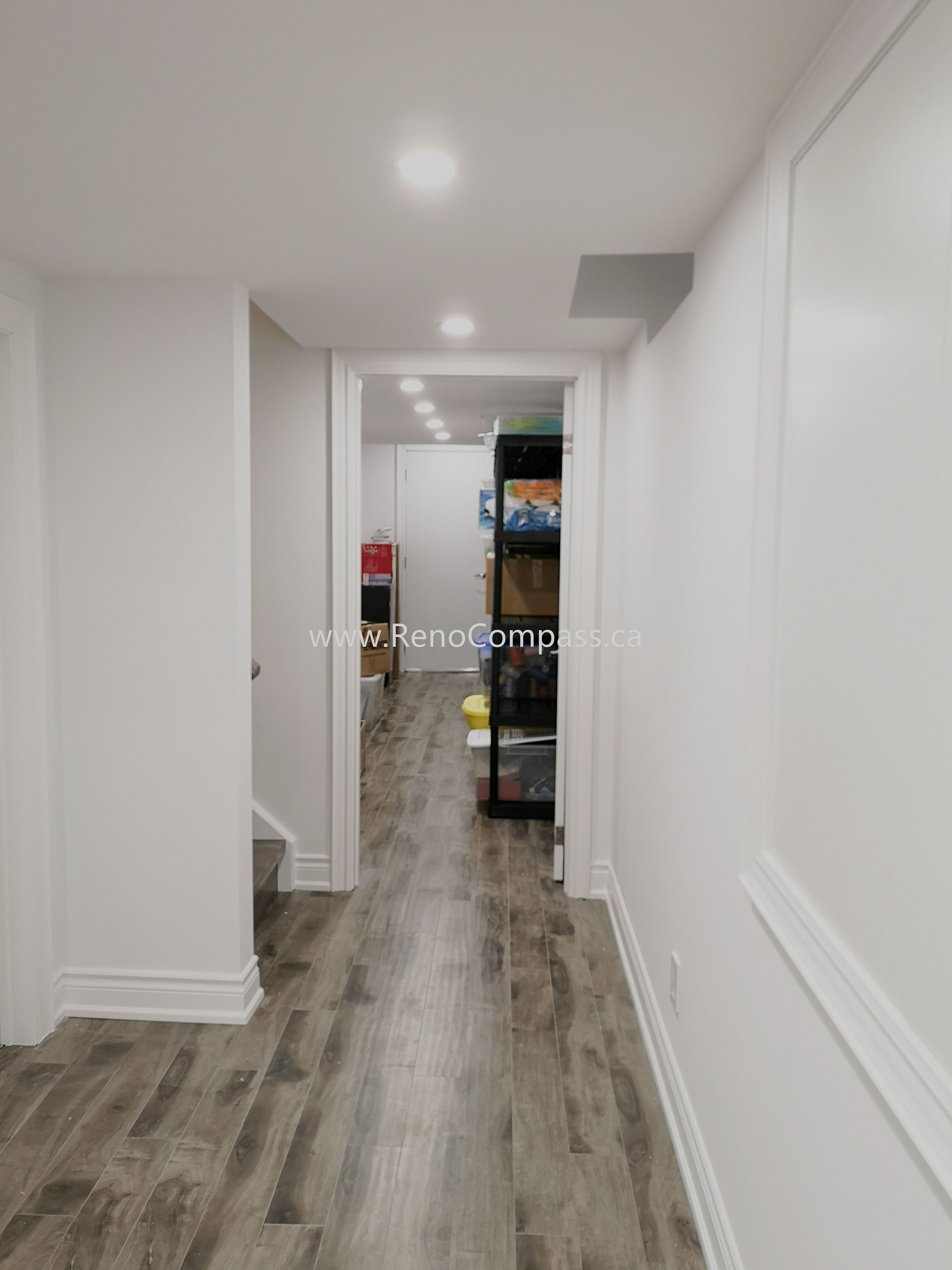 This Vaughan basement renovation features a clean and modern hallway design with durable wood-style flooring, smooth white walls, and recessed ceiling lighting for a bright and welcoming atmosphere. The upgraded basement corridor enhances overall flow and accessibility while maintaining a contemporary finish throughout the space. Completed by Reno Compass Inc., this renovation showcases quality craftsmanship and thoughtful design, creating a polished and functional basement living environment that complements the entire home renovation.