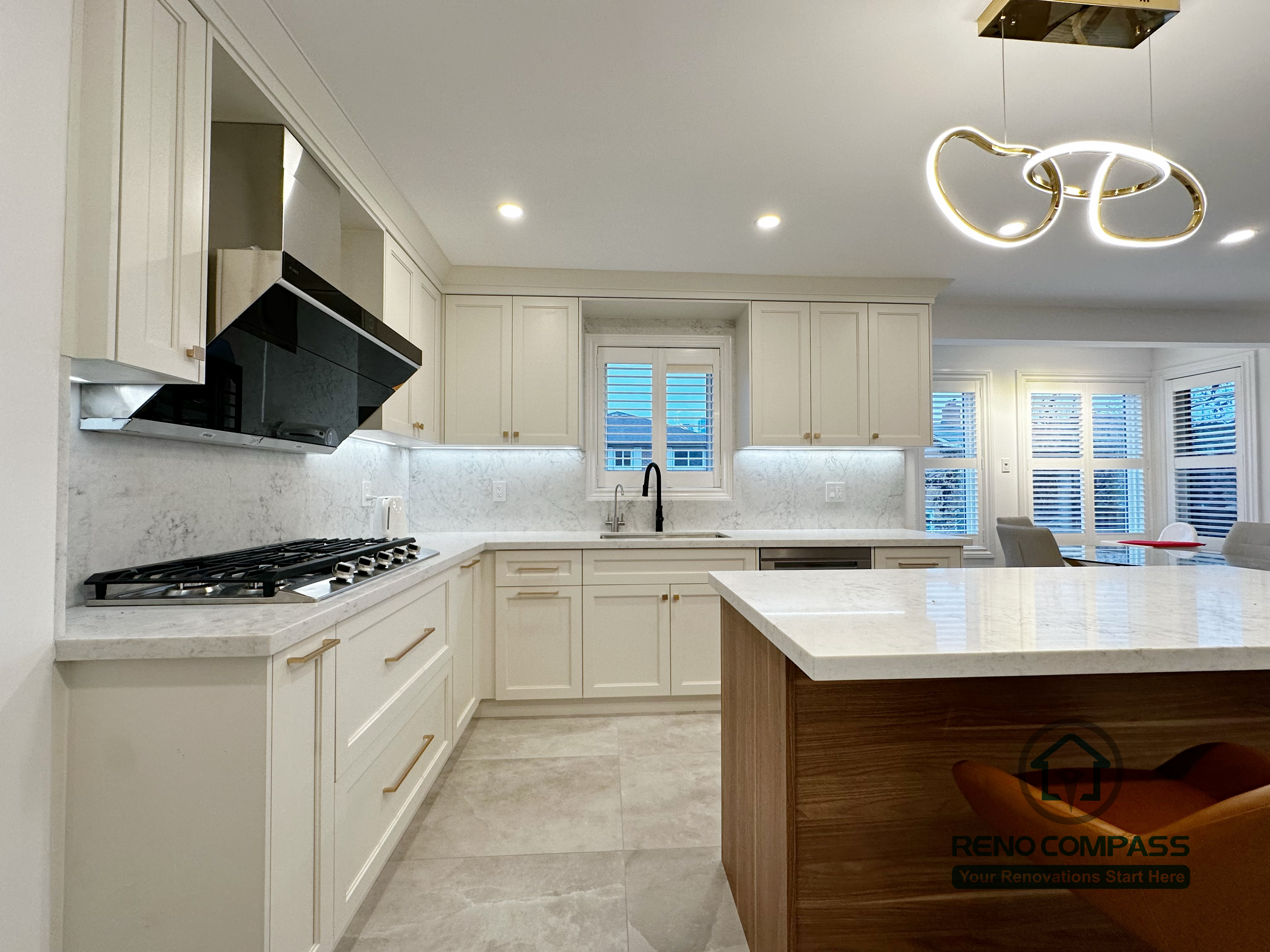 This Markham kitchen renovation showcases a spacious central island with quartz countertop, custom wood base cabinetry, and an open-concept layout that connects seamlessly to the living area. The design balances white perimeter cabinets with warm wood tones, improving both storage capacity and visual depth. Recessed lighting and modern pendant fixtures enhance overall brightness and functionality, making the kitchen ideal for daily cooking and entertaining.