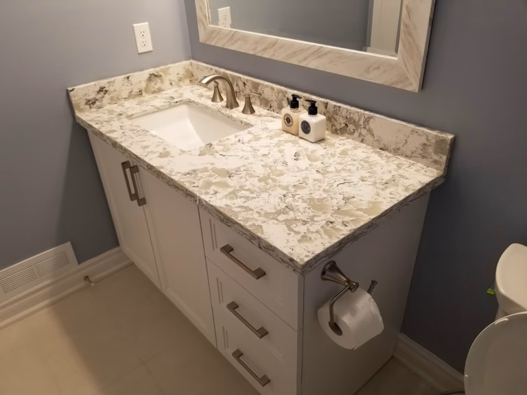 This Mississauga bathroom renovation showcases a custom vanity with a premium quartz countertop, modern undermount sink, and brushed metal fixtures. The elegant stone surface adds durability and luxury, while the clean cabinetry design provides practical storage and a timeless contemporary look.

Completed by Reno Compass Inc., this bathroom upgrade combines high-quality materials, precise installation, and refined finishing details to create a stylish and functional everyday space.