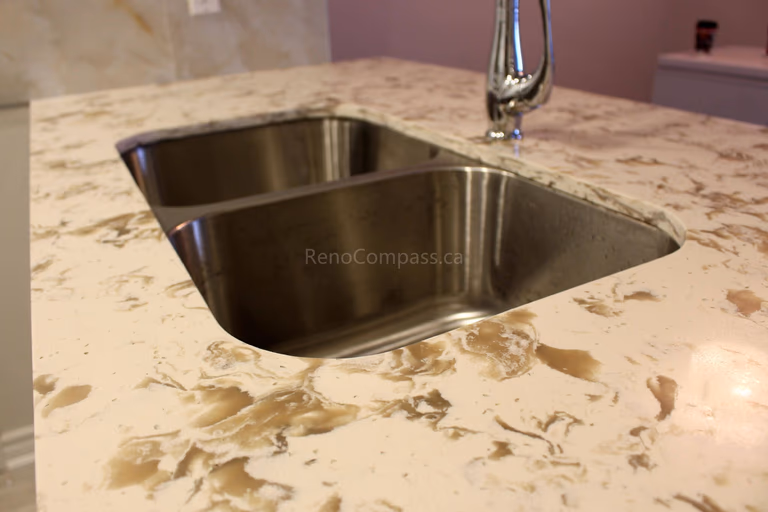 Close-up view of a beautifully designed quartz countertop featuring a deep double stainless steel sink and a modern chrome faucet. This Mississauga kitchen renovation showcases premium materials and a sleek, functional design for contemporary living.