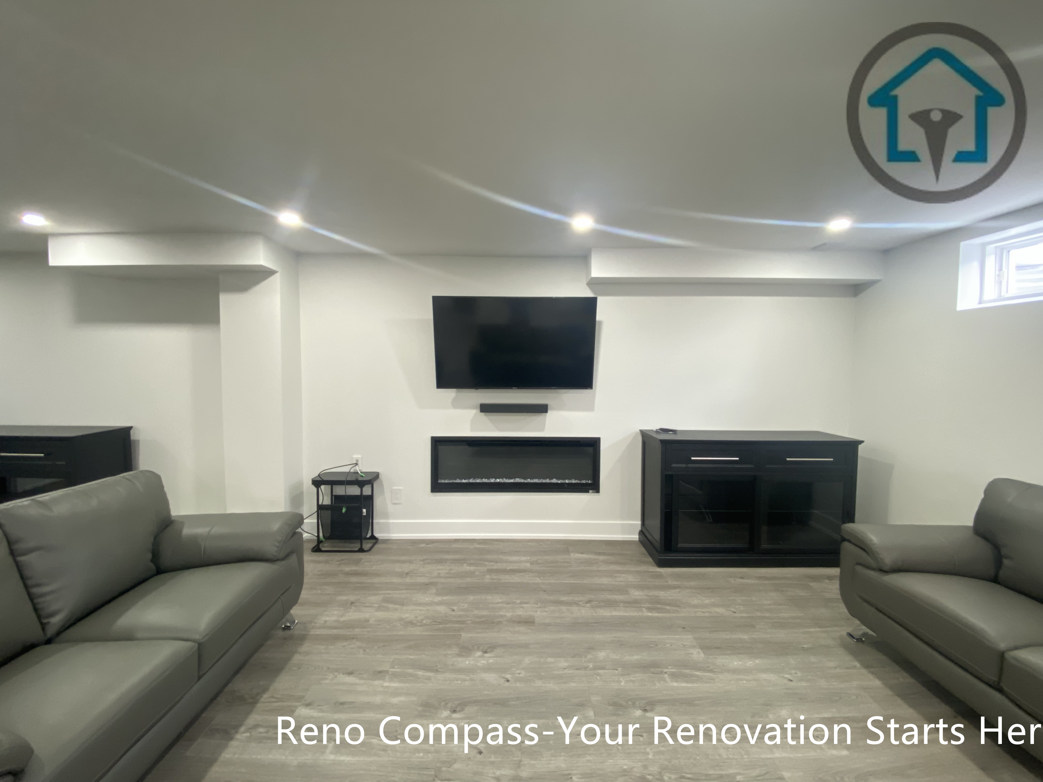 This image highlights a finished basement home theatre and entertainment area in Newmarket completed by a professional Toronto renovation company. The space features a wall-mounted TV, modern linear fireplace, custom storage cabinets, and recessed ceiling lighting. Paired with wood-look flooring and a clean, symmetrical layout, this basement entertainment zone is ideal for movie nights, family relaxation, or enhancing overall basement functionality.