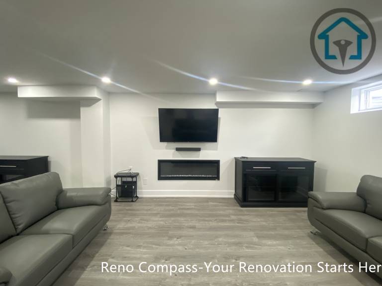 This image highlights a finished basement home theatre and entertainment area in Newmarket completed by a professional Toronto renovation company. The space features a wall-mounted TV, modern linear fireplace, custom storage cabinets, and recessed ceiling lighting. Paired with wood-look flooring and a clean, symmetrical layout, this basement entertainment zone is ideal for movie nights, family relaxation, or enhancing overall basement functionality.