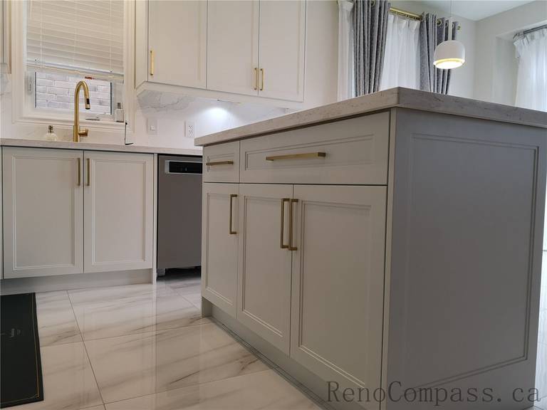 This Aurora kitchen renovation highlights custom island cabinetry with shaker-style doors, quartz countertops, and elegant brushed gold hardware. The modern layout integrates functional storage, under-cabinet lighting, and marble-style flooring to create a clean and sophisticated space. Completed by a professional Toronto renovation company focused on premium finishes, practical design, and high-quality craftsmanship.