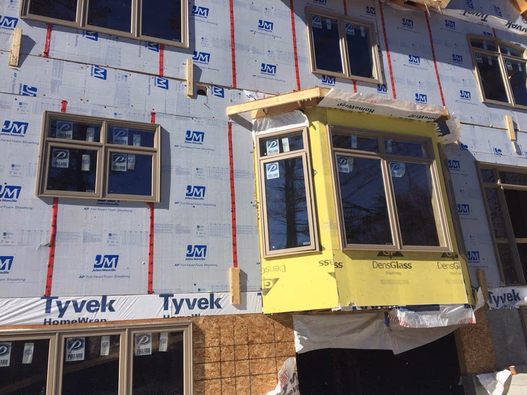 Construction phase of a Toronto custom home rebuild project, showing exterior structural work, window installation, and insulation preparation before the final façade installation. This stage is part of a professional Toronto design build process, demonstrating the structural craftsmanship and building expertise delivered by an experienced Toronto Renovation Company during a whole house renovation Toronto project.