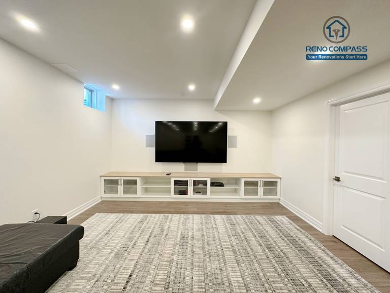 This Bradford basement renovation features a bright open-concept layout combining a custom kitchenette and spacious living area. White shaker cabinets, quartz countertops, and integrated storage create a clean and functional cooking space, while recessed lighting and wide-plank flooring enhance overall brightness. Designed for everyday use and entertaining, this basement renovation maximizes comfort and usability for modern families.