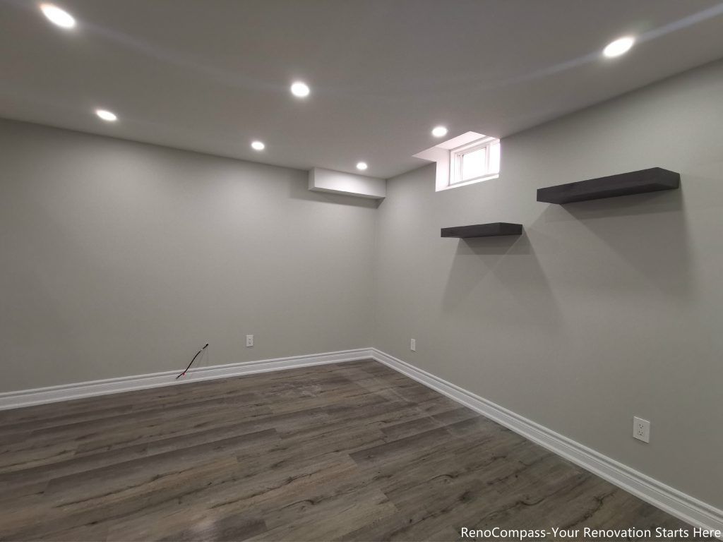 This Oakville basement renovation features a fully finished modern space with upgraded flooring, smooth ceilings, and recessed pot lights that create a bright and comfortable environment. The redesigned basement includes fresh wall finishes, clean trim work, and floating shelves for added functionality and storage. Completed by a professional Toronto renovation company, this basement upgrade enhances usable living space, improves lighting, and adds long-term value to the home while delivering a modern and versatile lower-level living area.
