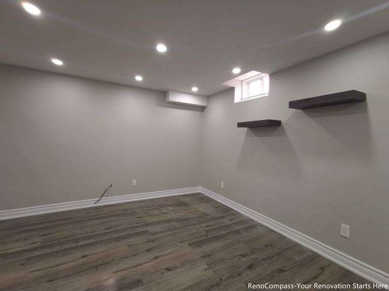 This Oakville basement renovation features a fully finished modern space with upgraded flooring, smooth ceilings, and recessed pot lights that create a bright and comfortable environment. The redesigned basement includes fresh wall finishes, clean trim work, and floating shelves for added functionality and storage. Completed by a professional Toronto renovation company, this basement upgrade enhances usable living space, improves lighting, and adds long-term value to the home while delivering a modern and versatile lower-level living area.