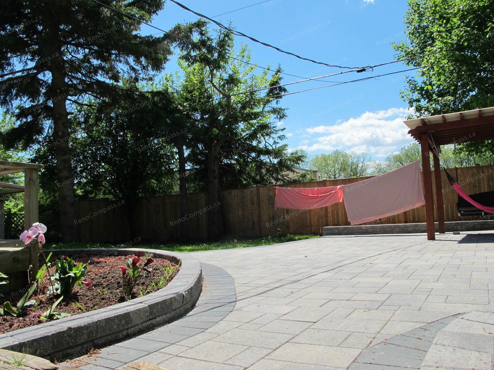 This Markham outdoor landscaping project showcases a beautifully designed interlock patio with curved stone borders and a custom garden bed layout. The spacious paved backyard provides a clean, modern outdoor living area perfect for relaxation and gatherings. Surrounded by mature trees and enhanced with professional garden design, this renovation highlights Reno Compass Inc.’s expertise in backyard transformation, combining durable interlock installation with elegant landscaping to create a functional and visually appealing outdoor space.