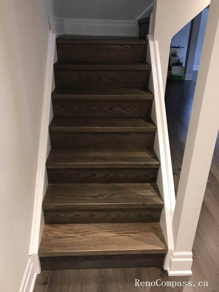 This photo showcases an upgraded hardwood staircase connecting the renovated basement to the main floor in a Richmond Hill home. The new wood steps, clean white trim, and modern finishing details create a seamless, durable, and stylish transition between levels. Completed by Reno Compass Inc.