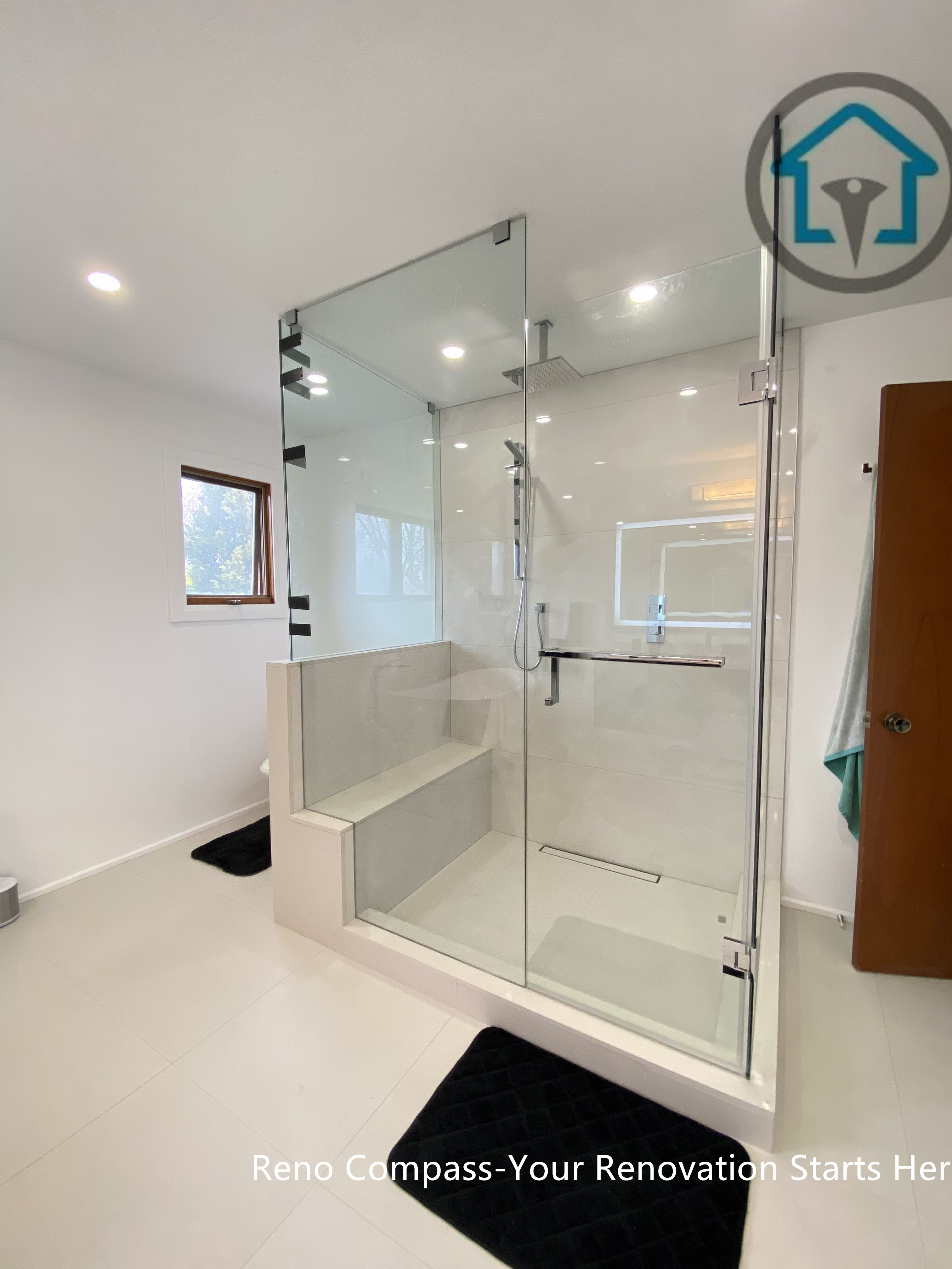 Modern bathroom renovation in Brampton showcasing a frameless glass walk-in shower with a built-in bench and curbless entry. The symmetrical layout, large-format tiles, and recessed ceiling lights enhance visual balance and spatial openness. Completed by a trusted Toronto renovation company, this shower design focuses on accessibility, safety, and long-term everyday functionality.