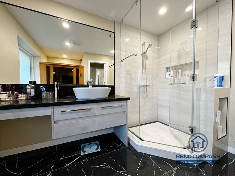 Bathroom vanity completed as part of a North York interior renovation. This design features a custom floating vanity, vessel sink, black countertop, and large wall mirror, paired with marble-look flooring and a glass shower enclosure. Built with a focus on durability, clean detailing, and daily usability by a professional Toronto renovation company.