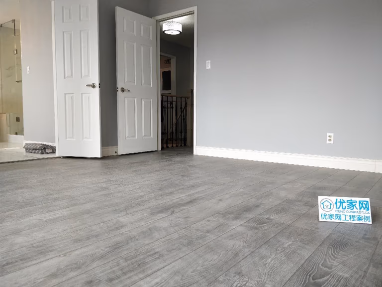 Bedroom interior renovation in Ajax featuring modern grey laminate flooring, newly painted walls, updated baseboards, and refreshed interior doors. The clean and minimalist upgrade enhances brightness and durability, completed by a professional Toronto renovation company specializing in residential interior remodeling.