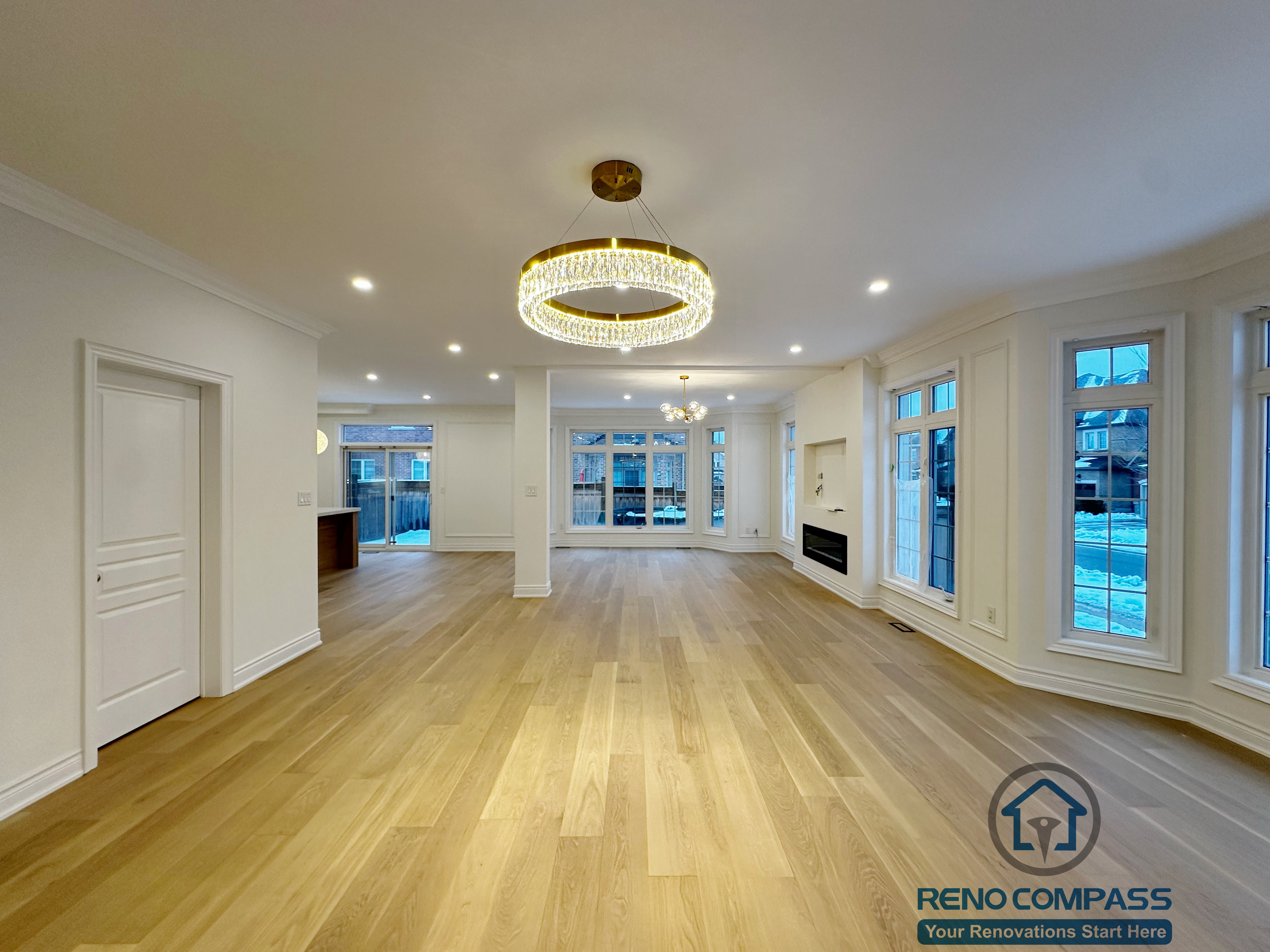 Spacious open-concept living and dining area completed as part of a Vaughan interior renovation, featuring wide-plank hardwood flooring, recessed ceiling lights, modern chandelier, and large windows that bring in natural light. The layout enhances flow, brightness, and functionality, reflecting the quality workmanship of a professional Toronto renovation company.
