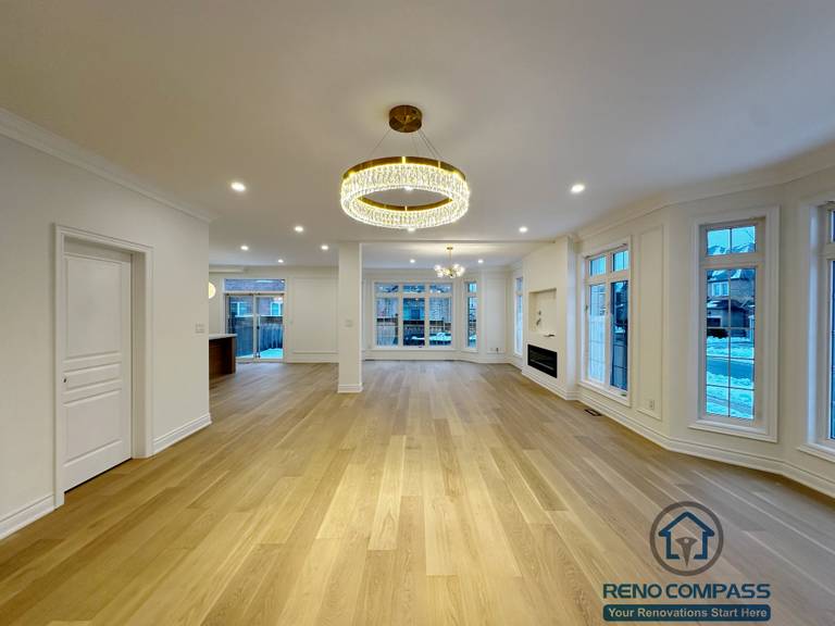 Spacious open-concept living and dining area completed as part of a Vaughan interior renovation, featuring wide-plank hardwood flooring, recessed ceiling lights, modern chandelier, and large windows that bring in natural light. The layout enhances flow, brightness, and functionality, reflecting the quality workmanship of a professional Toronto renovation company.