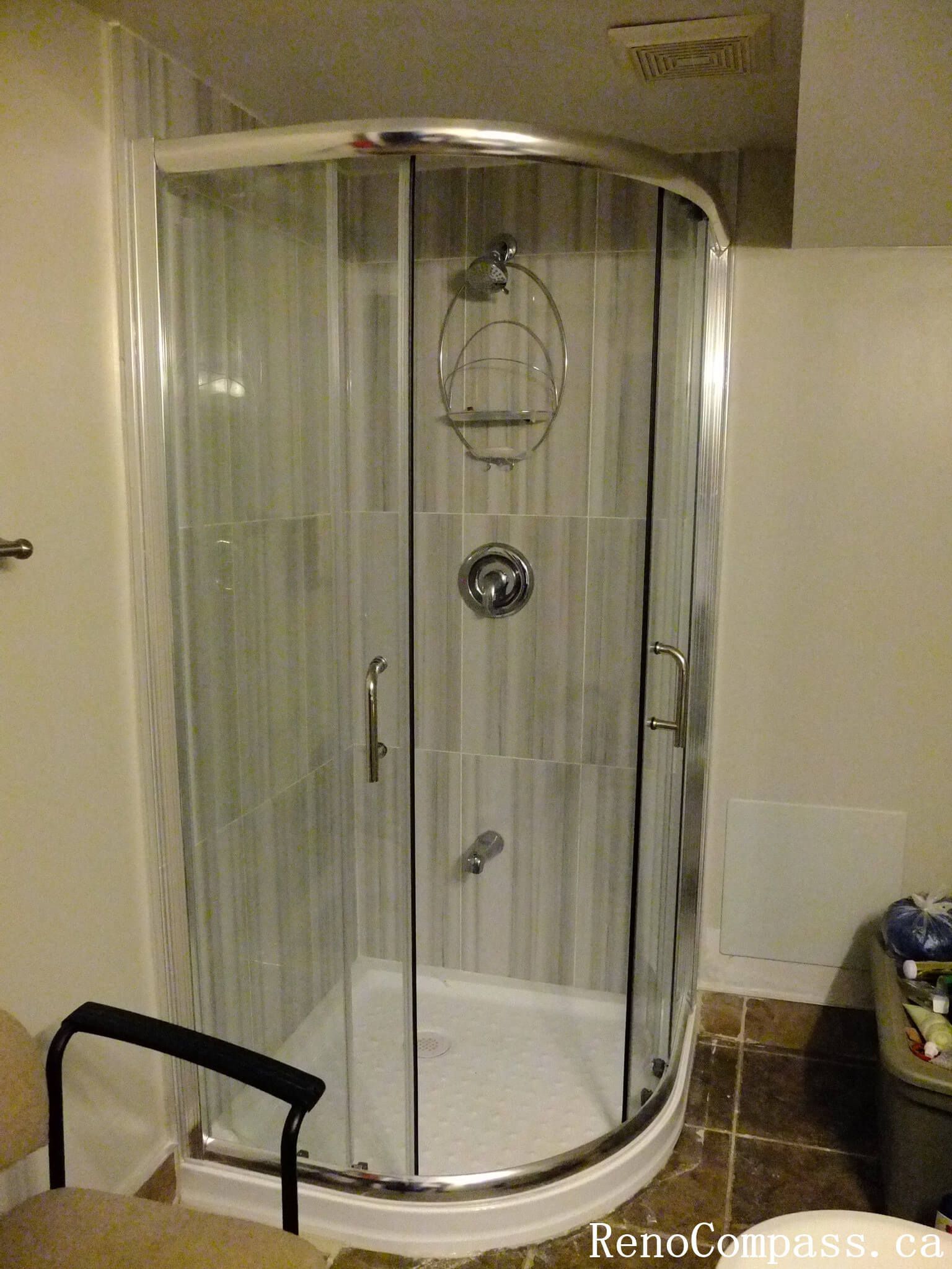 Finished shower enclosure from a North York bathroom renovation, featuring a curved glass shower door, chrome fixtures, and a compact layout designed for functionality and everyday comfort.