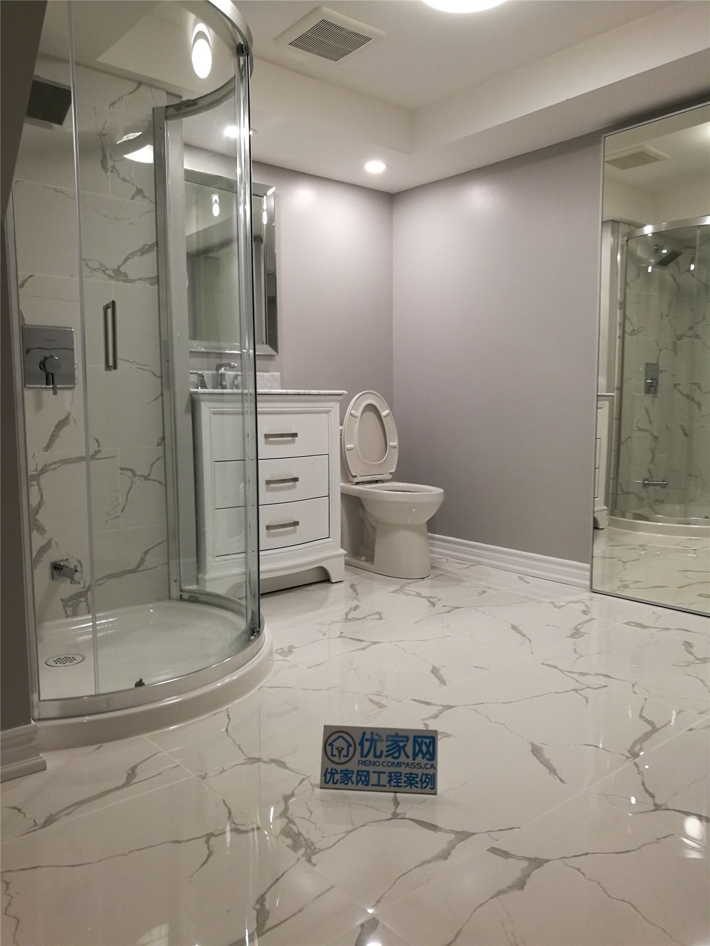 This bathroom shower renovation in New market combines elegant marble-pattern wall tiles with smaller accent tiles to create a visually balanced design. The contrast between the large marble surface and the decorative small tiles adds texture and depth while defining different areas of the shower space.