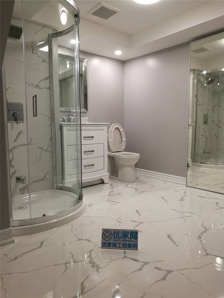 This bathroom shower renovation in New market combines elegant marble-pattern wall tiles with smaller accent tiles to create a visually balanced design. The contrast between the large marble surface and the decorative small tiles adds texture and depth while defining different areas of the shower space.