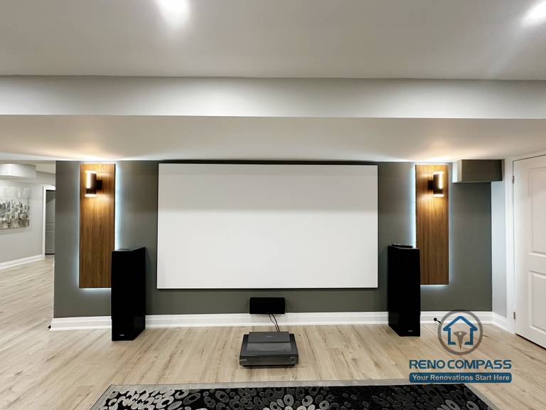 This Newmarket basement renovation features a custom home theater with a built-in projector screen, accent wall lighting, and integrated speaker placement. The finished basement is designed as a multifunctional family entertainment space, combining a modern media wall, comfortable seating area, and durable flooring for everyday use and movie nights.