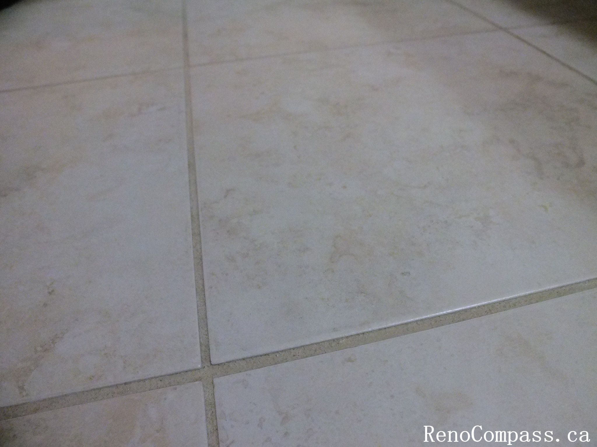Close-up view of newly installed ceramic floor tiles completed during a Richmond Hill interior renovation. The neutral-tone tiles feature a subtle natural stone texture with clean grout lines, providing a durable and elegant flooring solution for bathroom spaces. Completed by Reno Compass Inc., a trusted Toronto renovation company specializing in bathroom renovations and interior flooring upgrades.