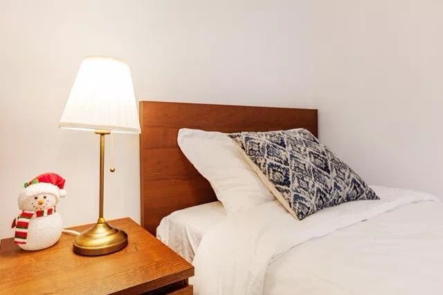 This Toronto interior renovation features a bright and cozy bedroom with minimalist styling. The space includes a comfortable bed setup, soft lighting, and a functional workspace corner, creating a relaxing and practical environment. Neutral tones and clean lines enhance the overall comfort, making it an ideal modern bedroom design for everyday living.