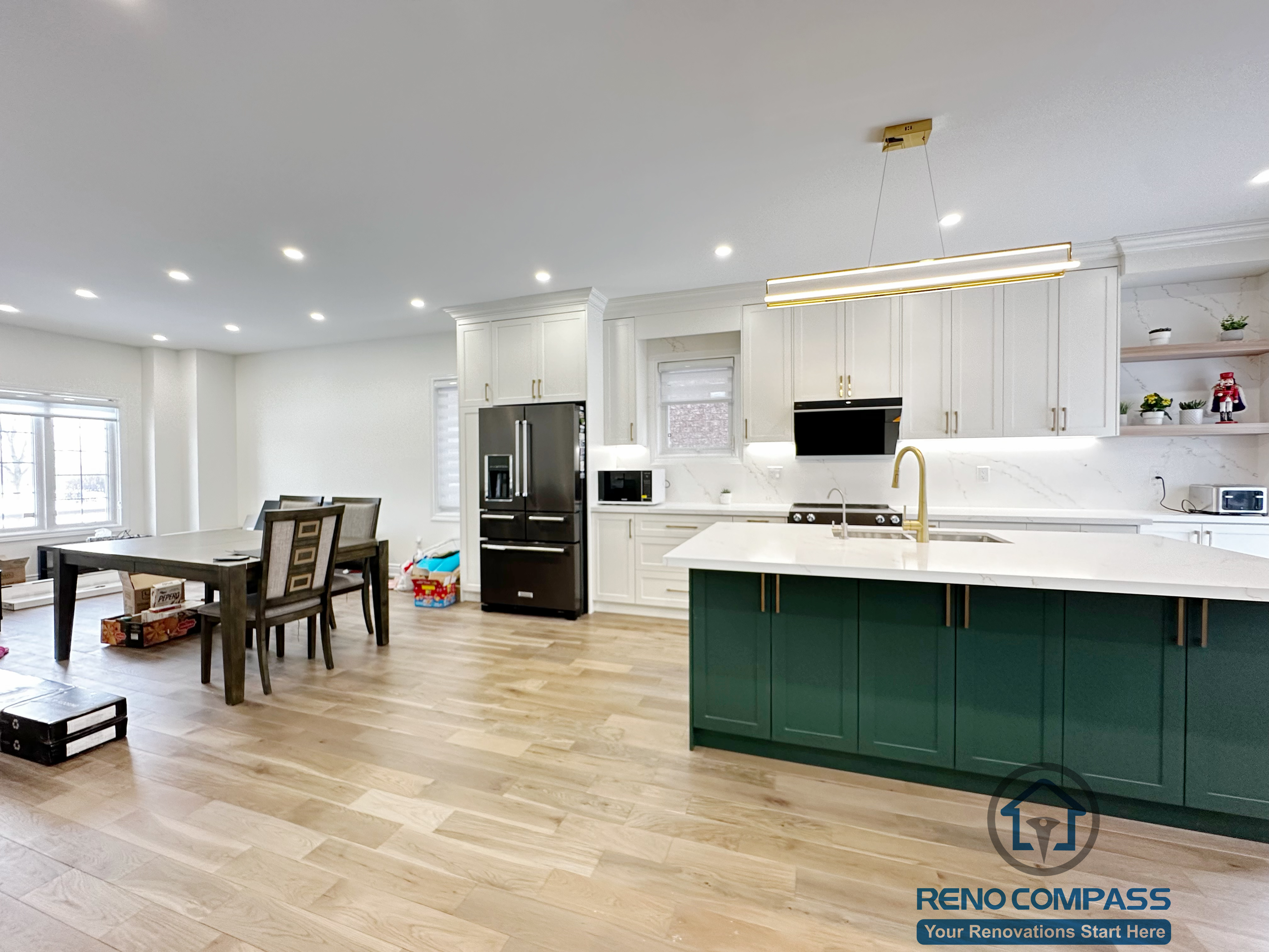 Interior renovation in Markham featuring a custom kitchen with full-height white cabinetry, a bold green island, quartz countertops, and modern pendant lighting. The design balances visual contrast with functionality, creating a bright and efficient central living space.