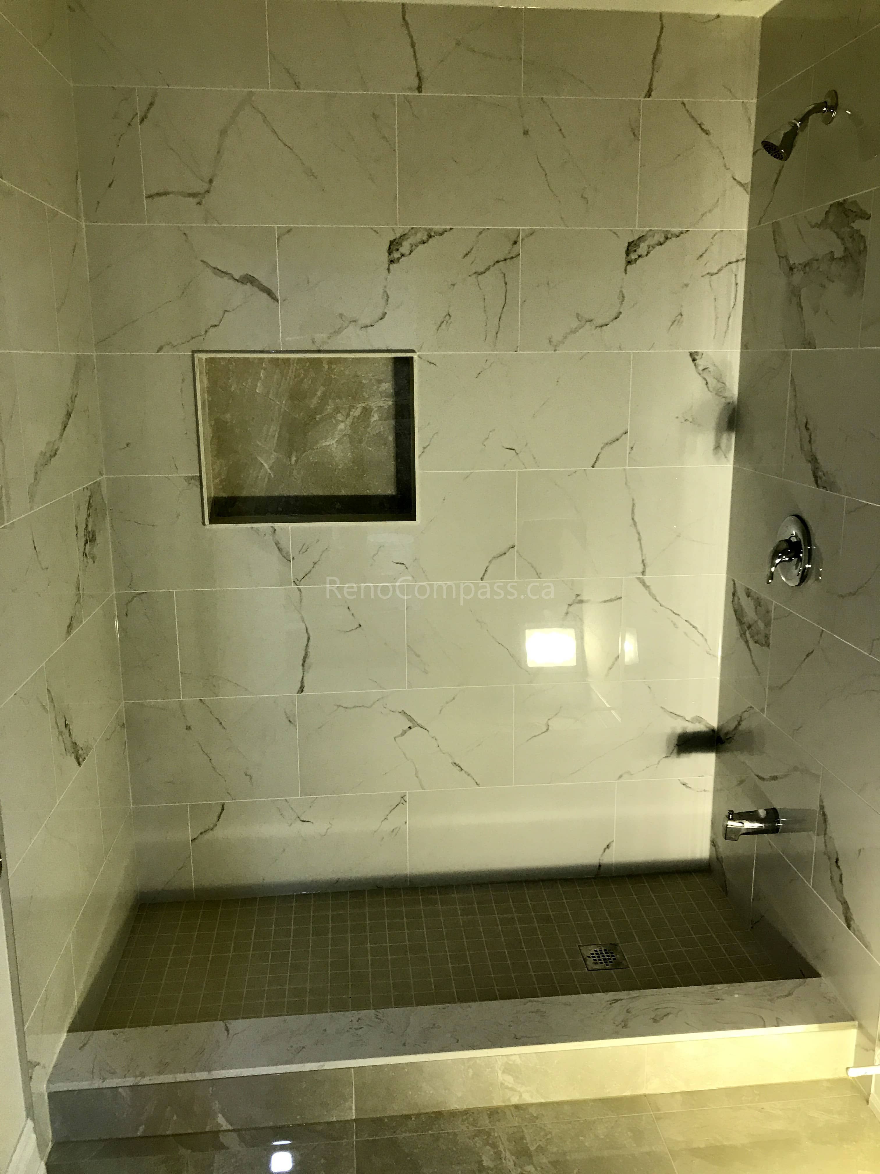 This Toronto bathroom renovation by Reno Compass features a custom walk-in shower finished with marble-look wall tiles and a built-in storage niche for everyday convenience. The raised shower base and textured floor tiles improve safety and drainage, while modern fixtures and clean tile lines create a luxurious, spa-like atmosphere. Designed for durability and comfort, this contemporary shower upgrade enhances both functionality and home value.