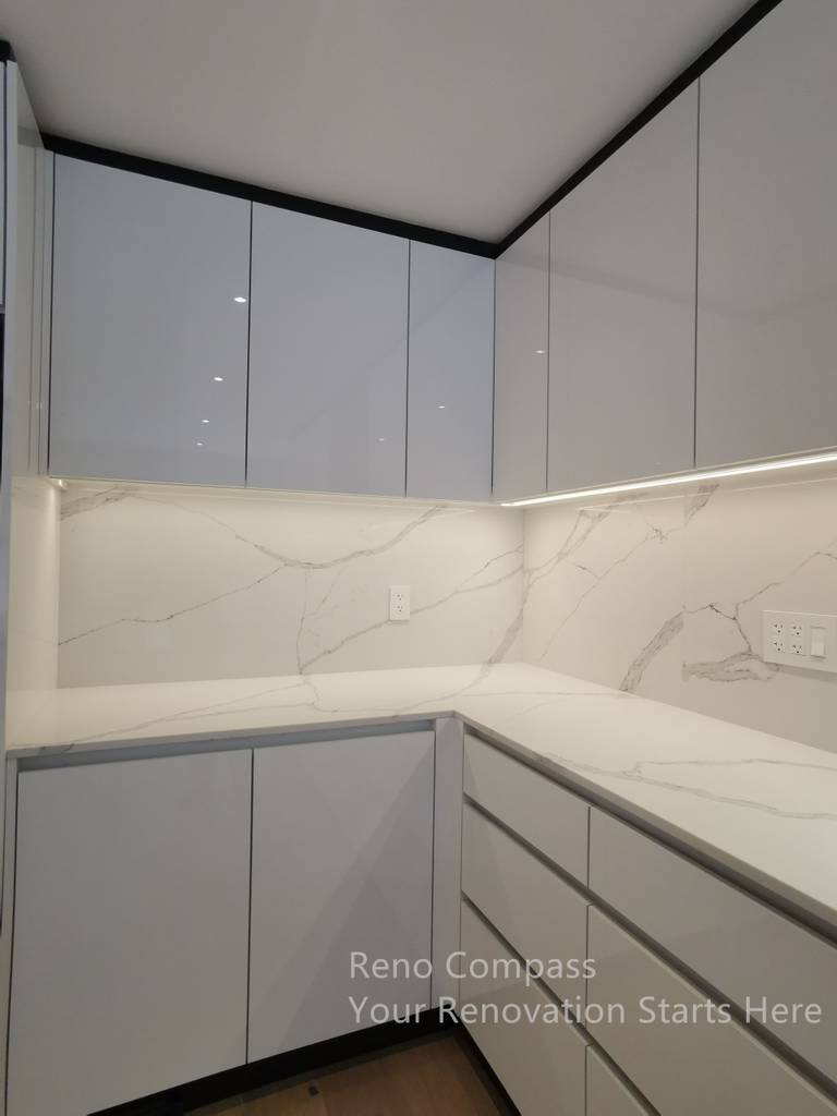 This image highlights the custom kitchen cabinetry completed as part of a Markham interior renovation. The sleek, handle-less upper cabinets create a clean and modern visual line, while integrated under-cabinet lighting enhances both functionality and ambiance. A marble-look stone backsplash and matching countertop provide durability and visual continuity, resulting in a refined, low-maintenance kitchen design tailored for everyday use.