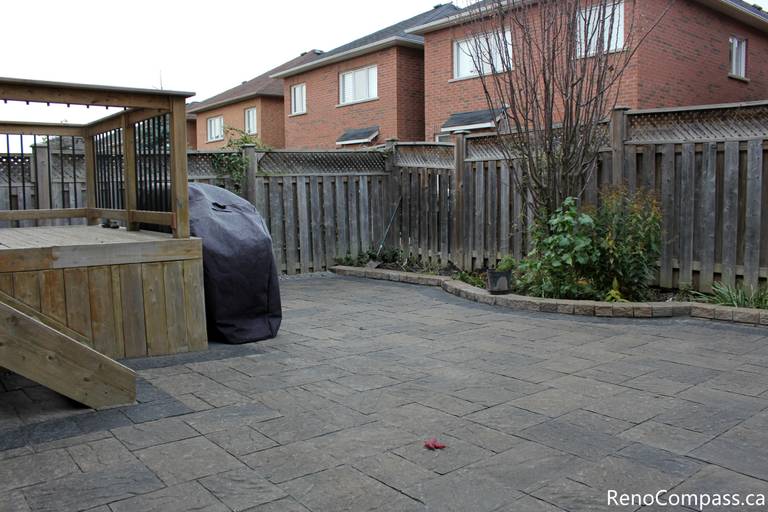 This Markham backyard landscaping project features a spacious interlocking stone patio seamlessly connected to a raised wooden deck. The clean paving layout creates a functional outdoor living area suitable for dining, relaxation, and year-round use. Completed by a Toronto renovation company, the interlocking patio enhances durability, drainage performance, and the overall usability of the backyard space.