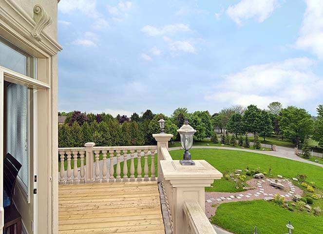 Second floor bedroom balcony from a luxury Toronto home renovation featuring elegant stone balustrades, natural wood decking, and expansive views of the surrounding landscape. The balcony creates a peaceful outdoor retreat connected directly to the interior living space. This custom home renovation project was completed by Reno Compass, a trusted Toronto Renovation Company specializing in luxury home rebuilds and interior renovations across the Greater Toronto Area.