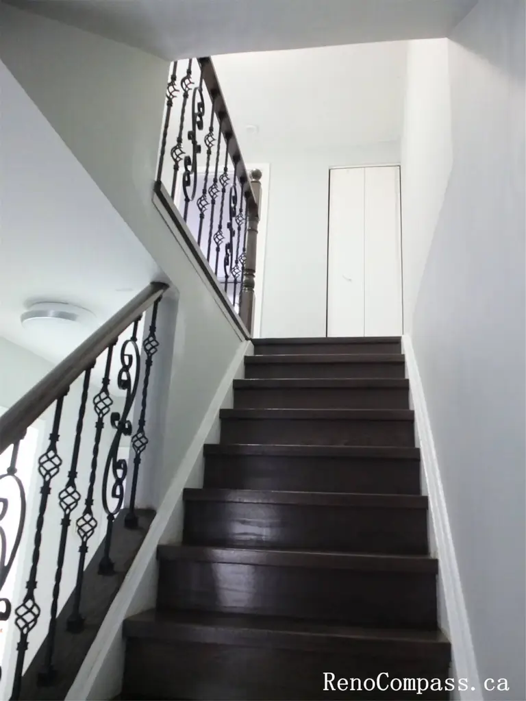 This North York interior renovation features an upgraded staircase with dark wood treads, white risers, and decorative iron railings. The contrast between materials enhances visual depth while maintaining safety and durability. Clean wall finishes and improved lighting help create a refined vertical transition between floors in this Toronto home renovation project.