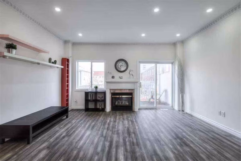 This Thornhill interior renovation showcases a spacious living room upgrade featuring new vinyl flooring, fresh wall painting, modern pot lights, and a refreshed fireplace feature wall. Large windows and sliding patio doors enhance natural light and openness, creating a bright and welcoming environment. Completed by a professional Toronto renovation team, this renovation highlights quality craftsmanship and modern interior design for comfortable family living.