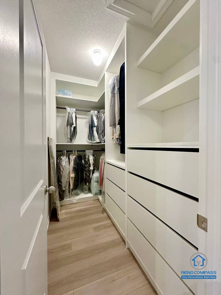 This Stouffville interior renovation features a custom walk-in closet with built-in shelving, drawers, and hanging storage designed for maximum organization and efficiency. Clean white cabinetry, wood-look flooring, and integrated lighting create a bright and functional dressing space. Completed by a professional Toronto renovation company, Reno Compass Inc., this custom storage solution reflects thoughtful interior planning and high-quality craftsmanship.