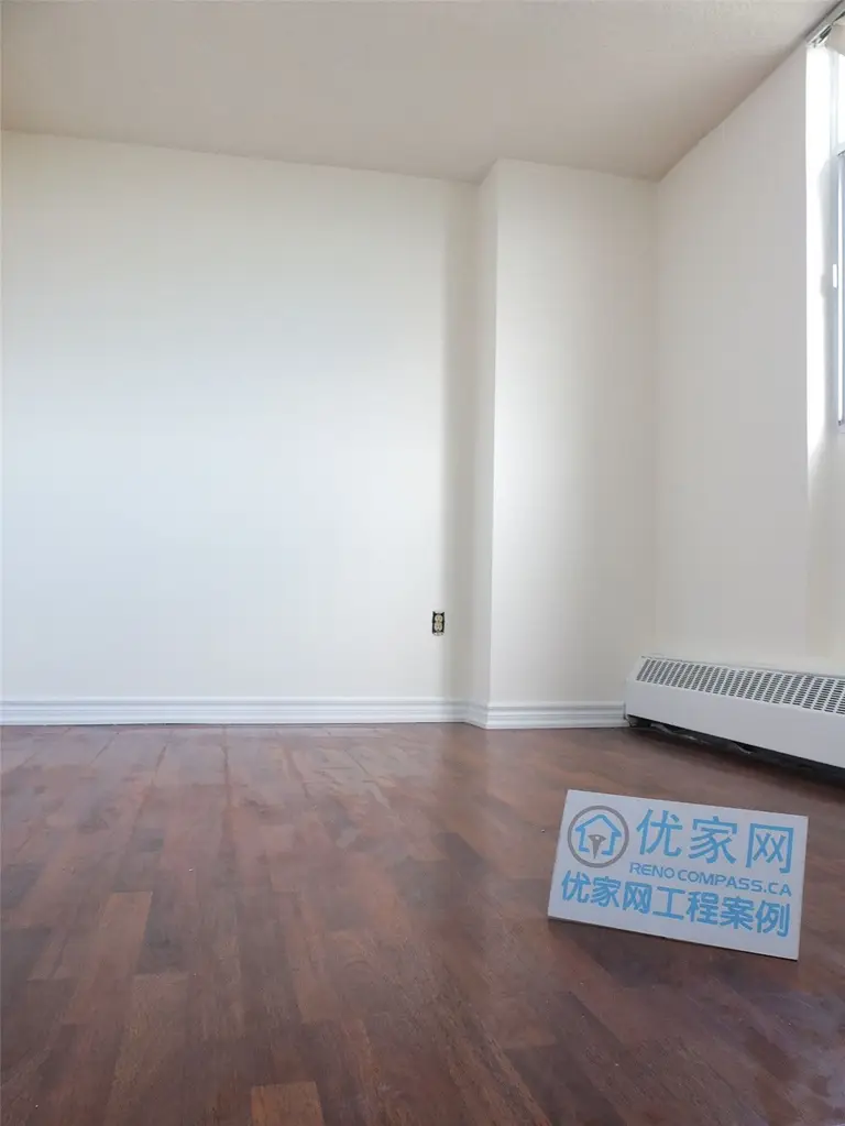 A bright and refreshed condo interior in Scarborough featuring newly installed flooring and clean white walls. This open living space benefits from large windows that enhance natural light, creating a warm and comfortable atmosphere. The renovation improves overall functionality and visual appeal, showcasing professional interior renovation work by a Toronto renovation company.