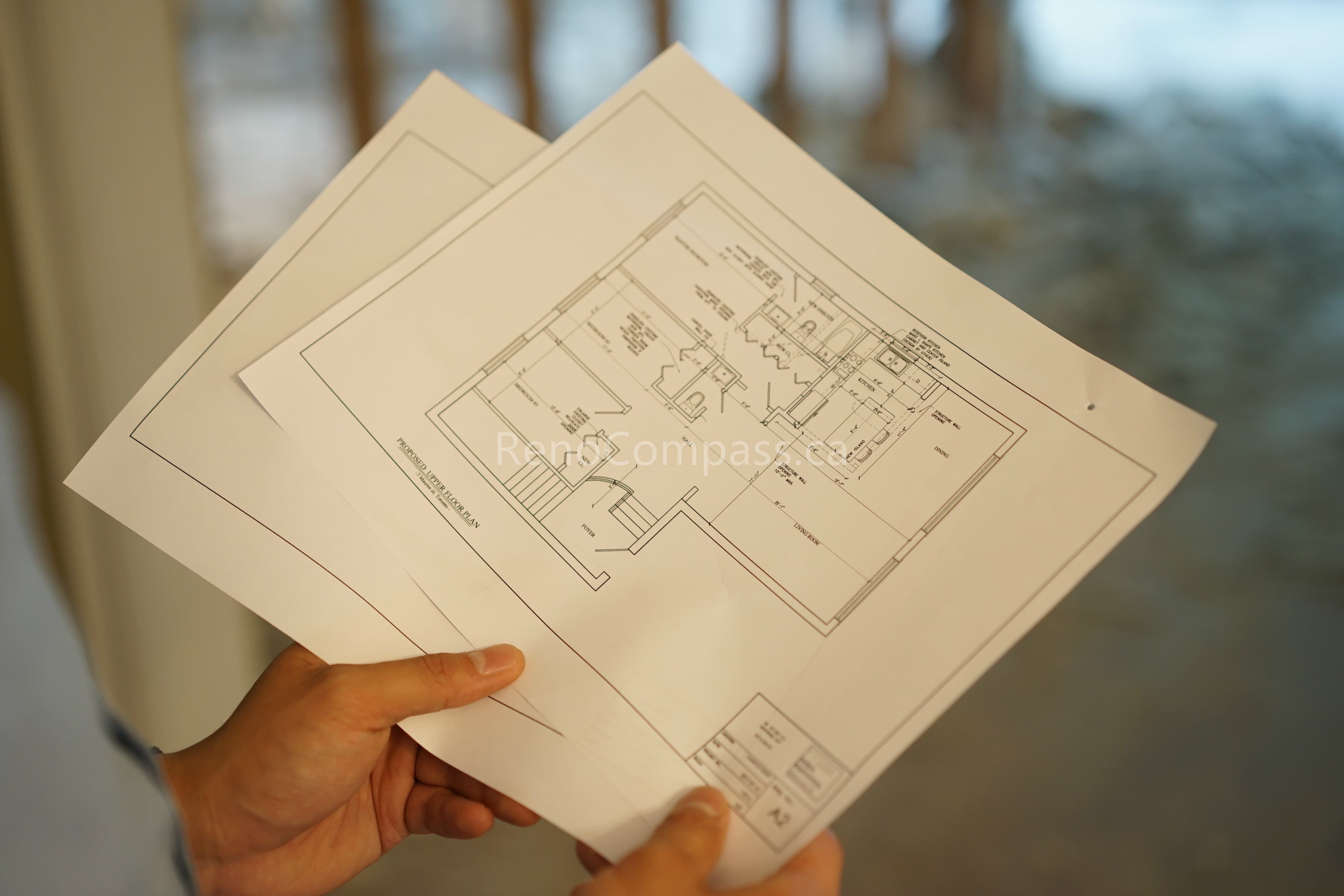 Hands holding detailed interior renovation floor plan drawings during a North York home renovation project. This image highlights the planning and layout stage handled by a professional Toronto renovation company, ensuring accurate space optimization, permit compliance, and high-quality interior renovation execution.