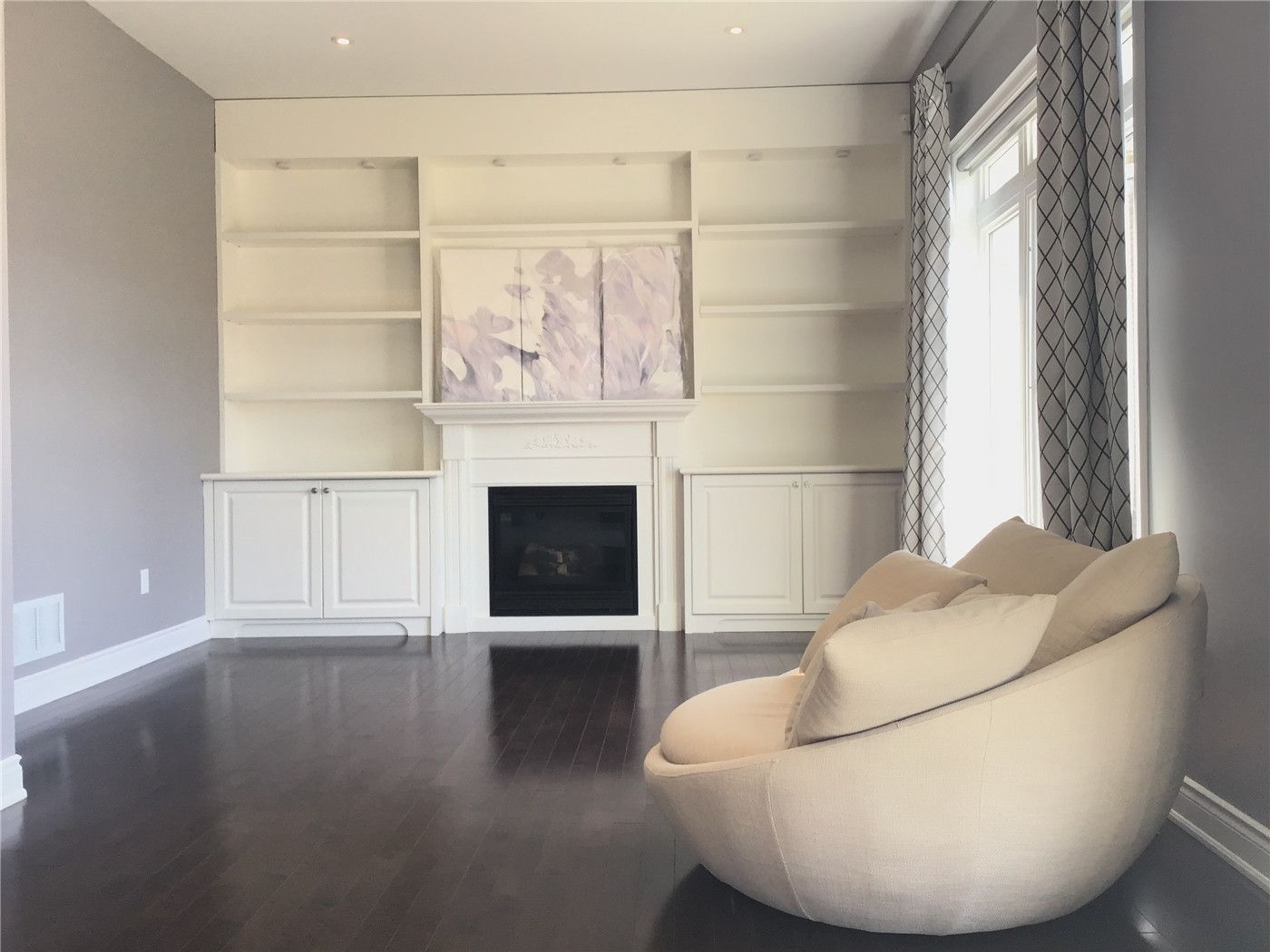 This Markham full home renovation features a refined living room with custom built-in shelving, a classic fireplace focal point, and rich hardwood flooring. The neutral color palette and integrated cabinetry create a clean, elegant, and highly functional space. Completed by a trusted Toronto Renovation Company, this design enhances both storage and visual appeal for modern living.