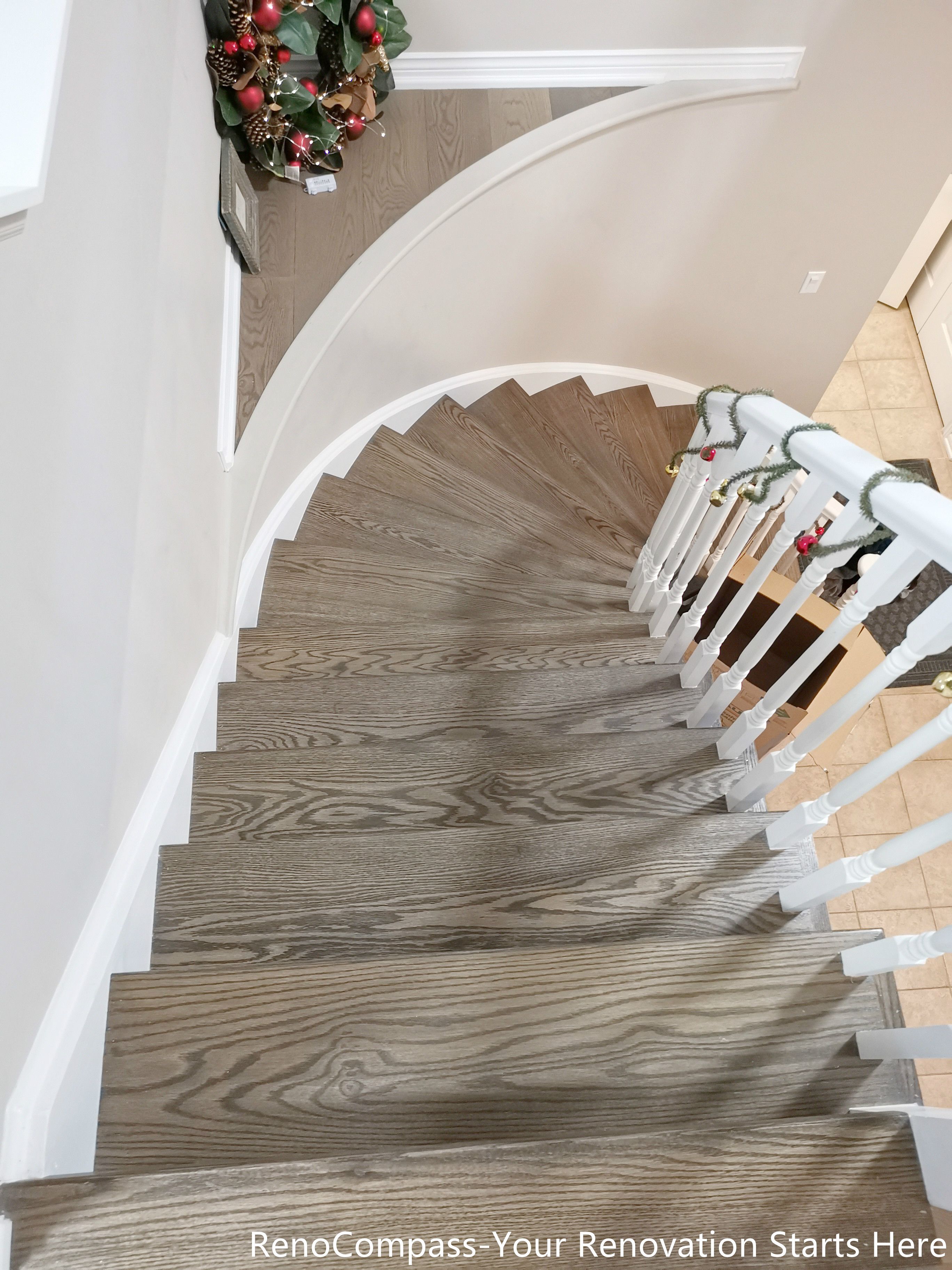 This top-down view highlights the craftsmanship of the curved staircase, showcasing natural wood treads paired with smooth white railings. The continuous curve creates a fluid visual rhythm, while the consistent wood grain enhances warmth and texture throughout the vertical space. Designed as part of the overall interior renovation, the staircase serves as both a functional connector and a refined architectural feature within the Oakville home.