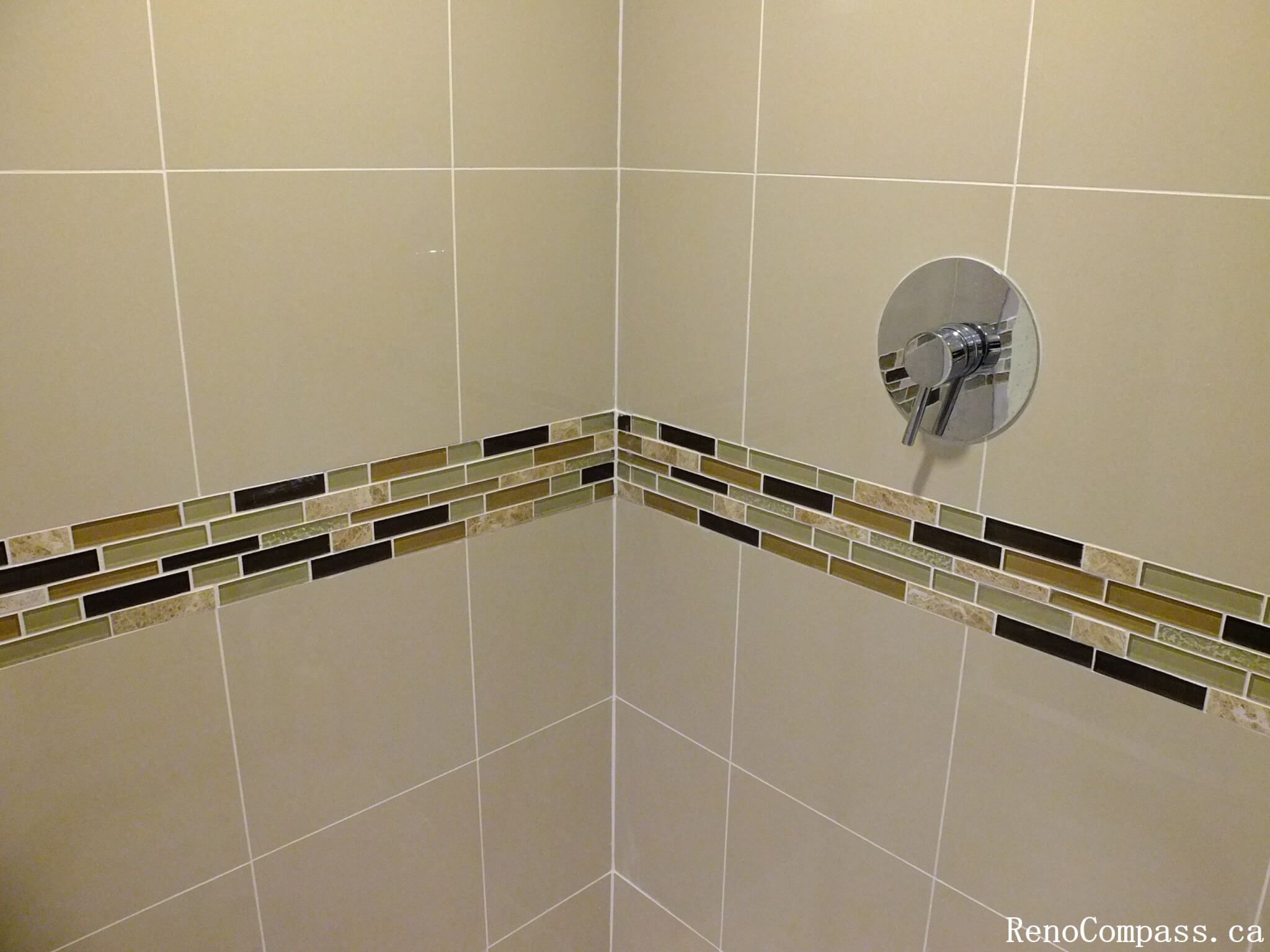 This Mississauga bathroom renovation highlights a clean and modern shower wall design featuring large-format beige tiles paired with a decorative mosaic accent strip. The horizontal mosaic band adds visual interest and depth while maintaining a balanced, neutral color palette. The chrome shower control fixture complements the tile work and provides a sleek, contemporary finish. This detail-focused installation demonstrates quality craftsmanship and thoughtful design, enhancing both the style and durability of the bathroom space.