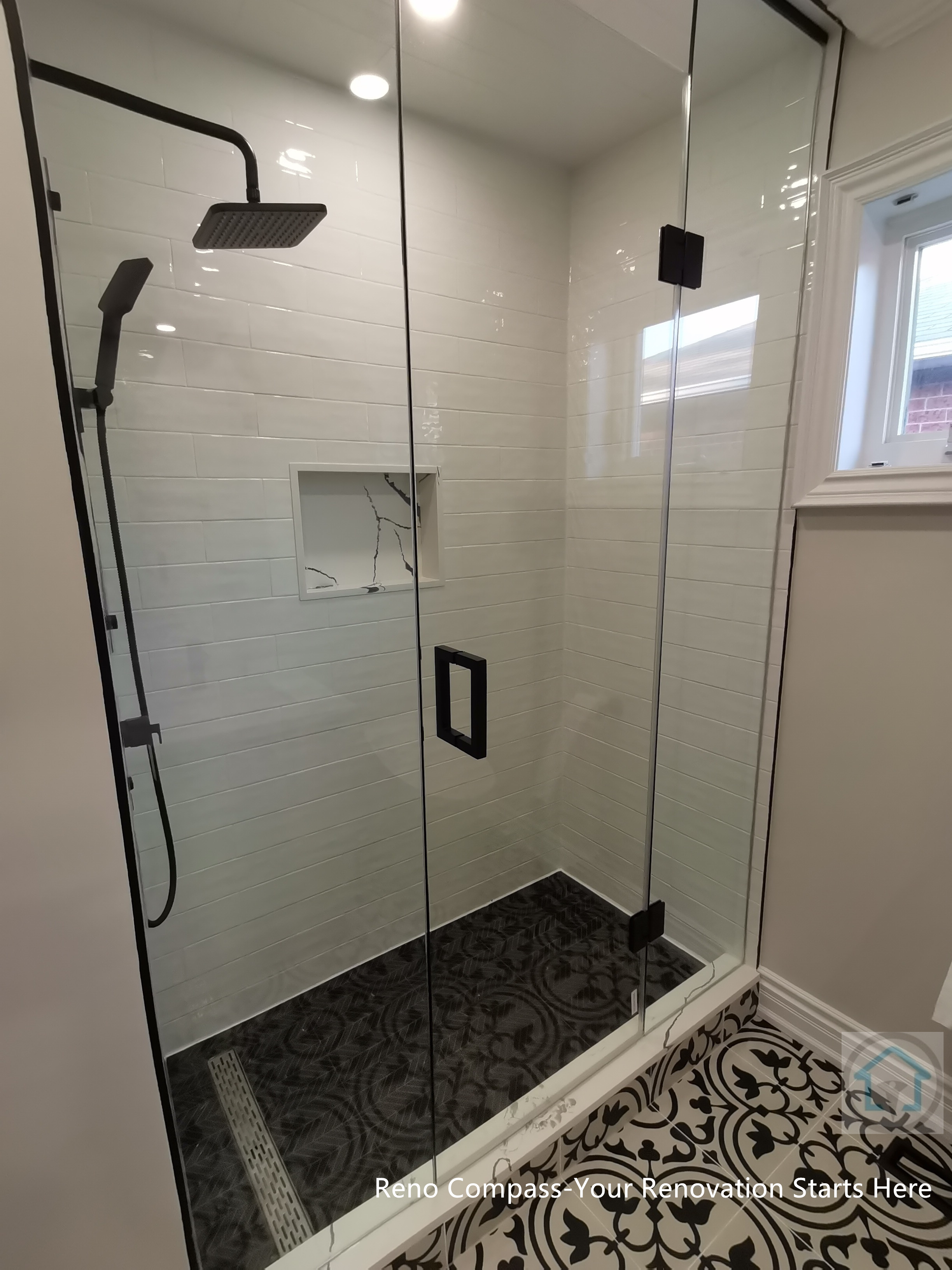 This Thornhill bathroom renovation features a glass-enclosed shower with modern black fixtures, a built-in niche, and clean subway-style wall tiles. The frameless design improves light flow and visual openness, while patterned floor tiles add contrast and character to the shower area.