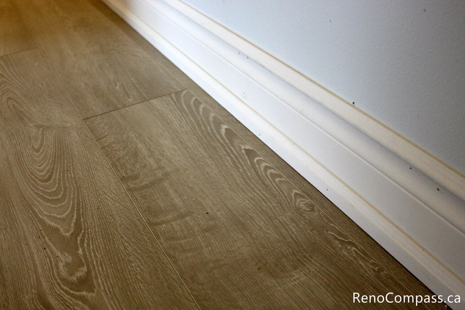 High-quality wide-plank wood-look flooring and custom baseboard installation for an interior renovation in Oshawa, Ontario. Professional craftsmanship by RenoCompass.ca to enhance home value and modern aesthetics.
