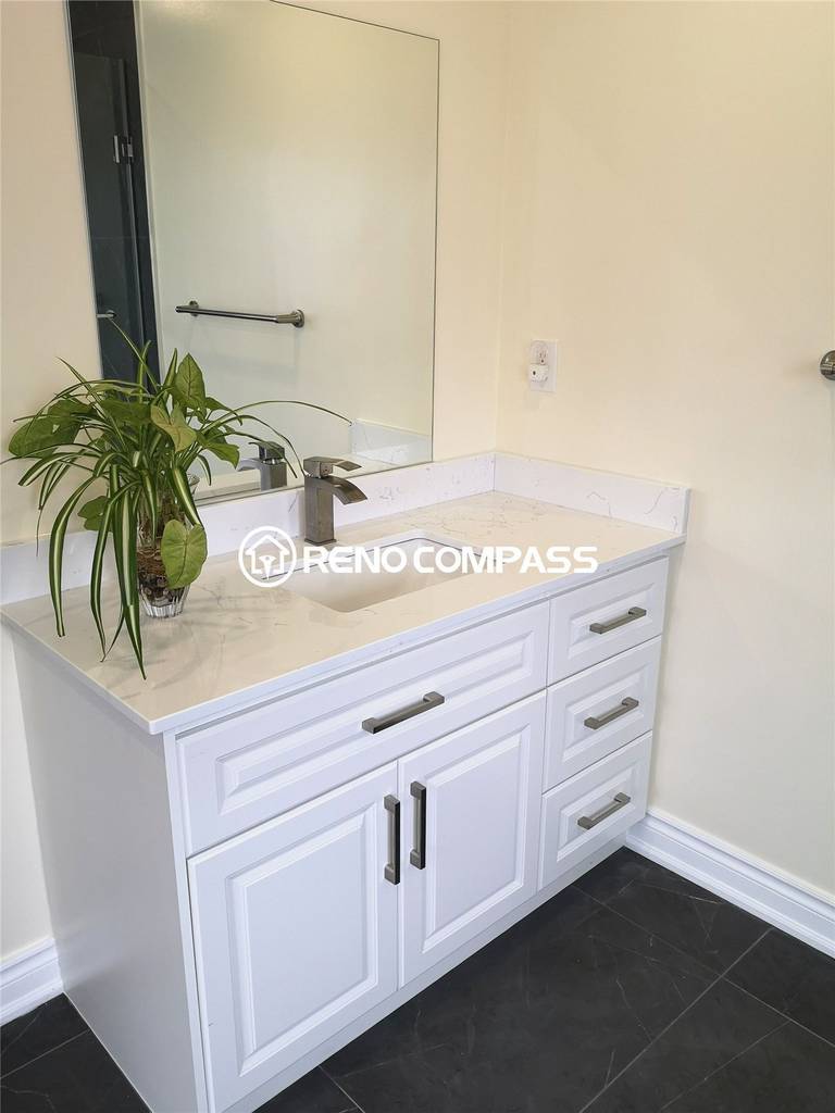 A bright and modern bathroom vanity installation in Richmond Hill featuring a sleek white cabinet, quartz countertop, and chrome faucet. Accented with greenery for a fresh, inviting look — another quality renovation by Reno Compass.
