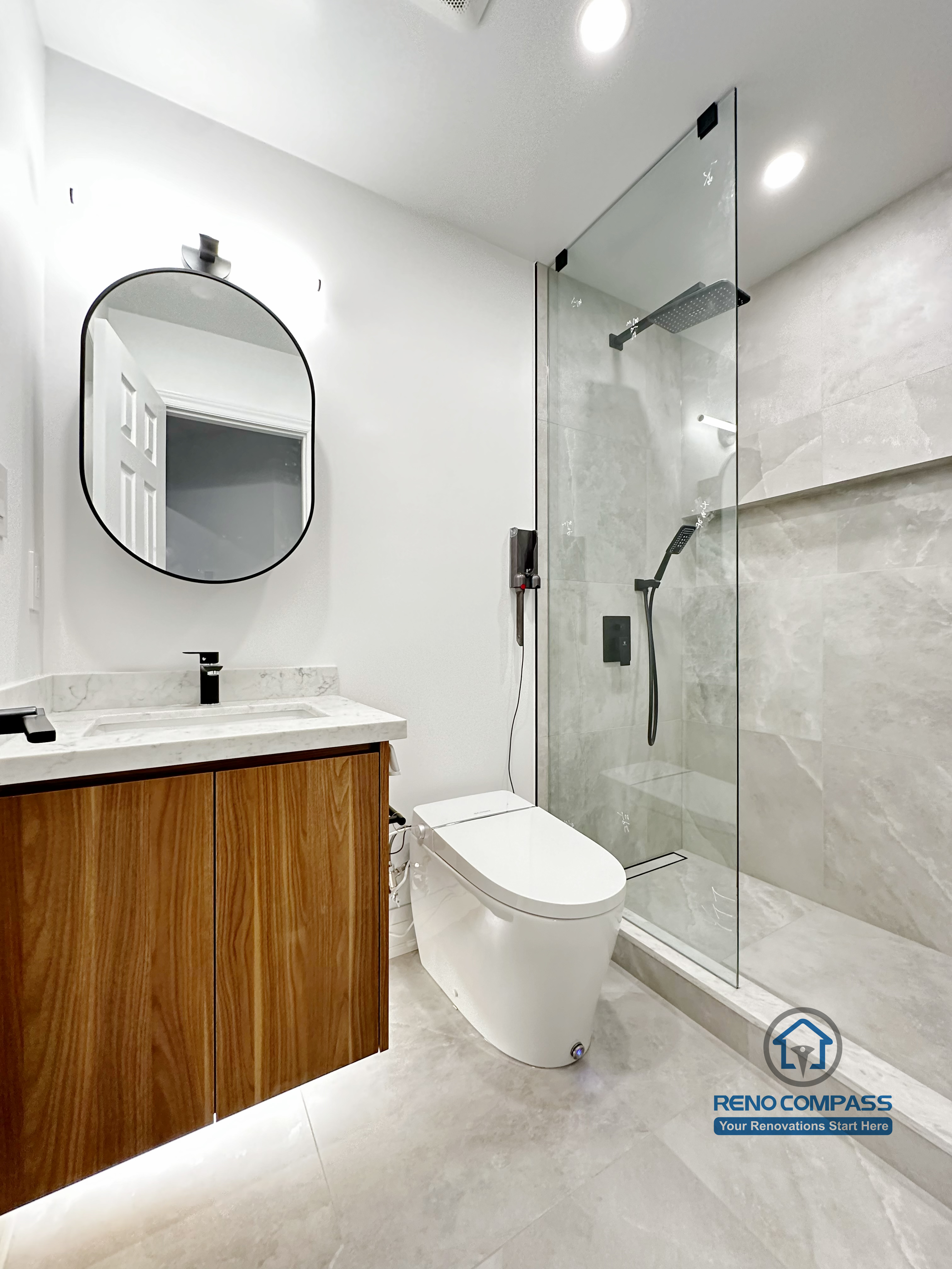 Bathroom renovation in Markham featuring a custom wood vanity with quartz countertop, vessel sink, brass fixtures, and a rounded backlit mirror. Vertical wood paneling and minimalist finishes create a warm, modern powder room with clean proportions and refined detailing.