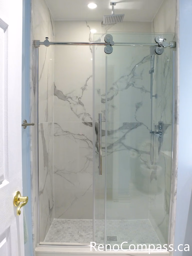 This Richmond Hill bathroom renovation features a sleek frameless glass shower enclosure, marble-look wall tiles, and a clean modern layout designed for comfort and durability. Completed by a professional Toronto renovation company, the space combines elegant finishes with practical functionality, creating a bright and contemporary bathroom upgrade for everyday living.