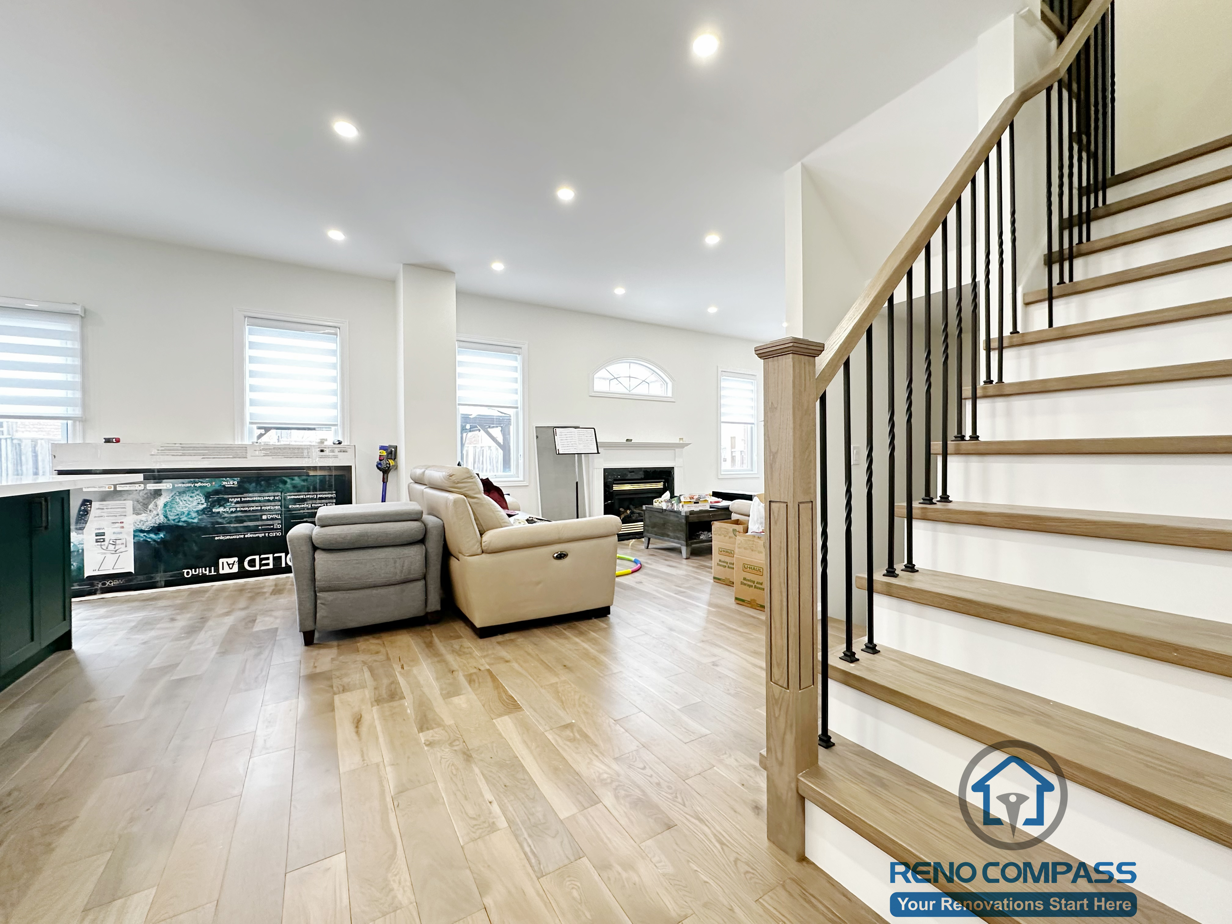 Interior renovation in Markham showcasing an open living area with wide-plank hardwood flooring, recessed ceiling lighting, and a custom staircase featuring wood treads and black metal balusters. The design emphasizes flow, structure, and everyday comfort.