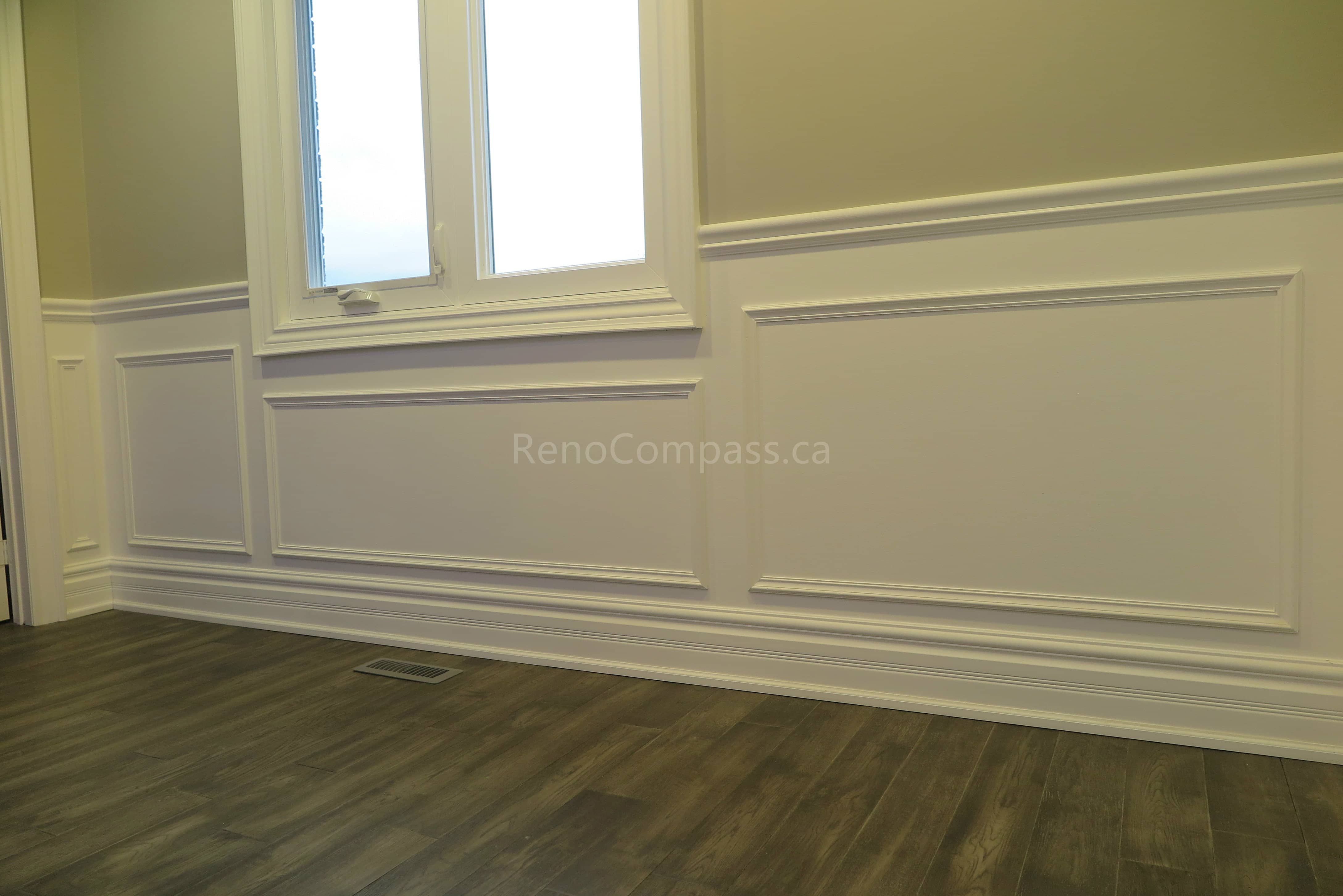 This Markham interior renovation showcases a bright and elegant living space featuring custom wall panel molding, crown molding details, and newly installed dark hardwood flooring. Recessed LED pot lights provide balanced lighting throughout the room, while large windows enhance natural light and openness. Completed by Reno Compass, a professional renovation contractor specializing in high-quality interior renovations and custom finishing services across Markham and the Greater Toronto Area.