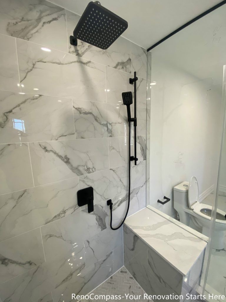 This Thornhill bathroom renovation showcases a detailed walk-in shower interior finished with marble-look porcelain wall tiles and a textured shower base. Matte black rain shower and handheld fixtures create a bold contrast against the light stone surfaces, adding a modern and refined aesthetic. The frameless glass enclosure enhances brightness and visual openness, while the carefully selected materials ensure durability, easy maintenance, and long-term daily comfort.