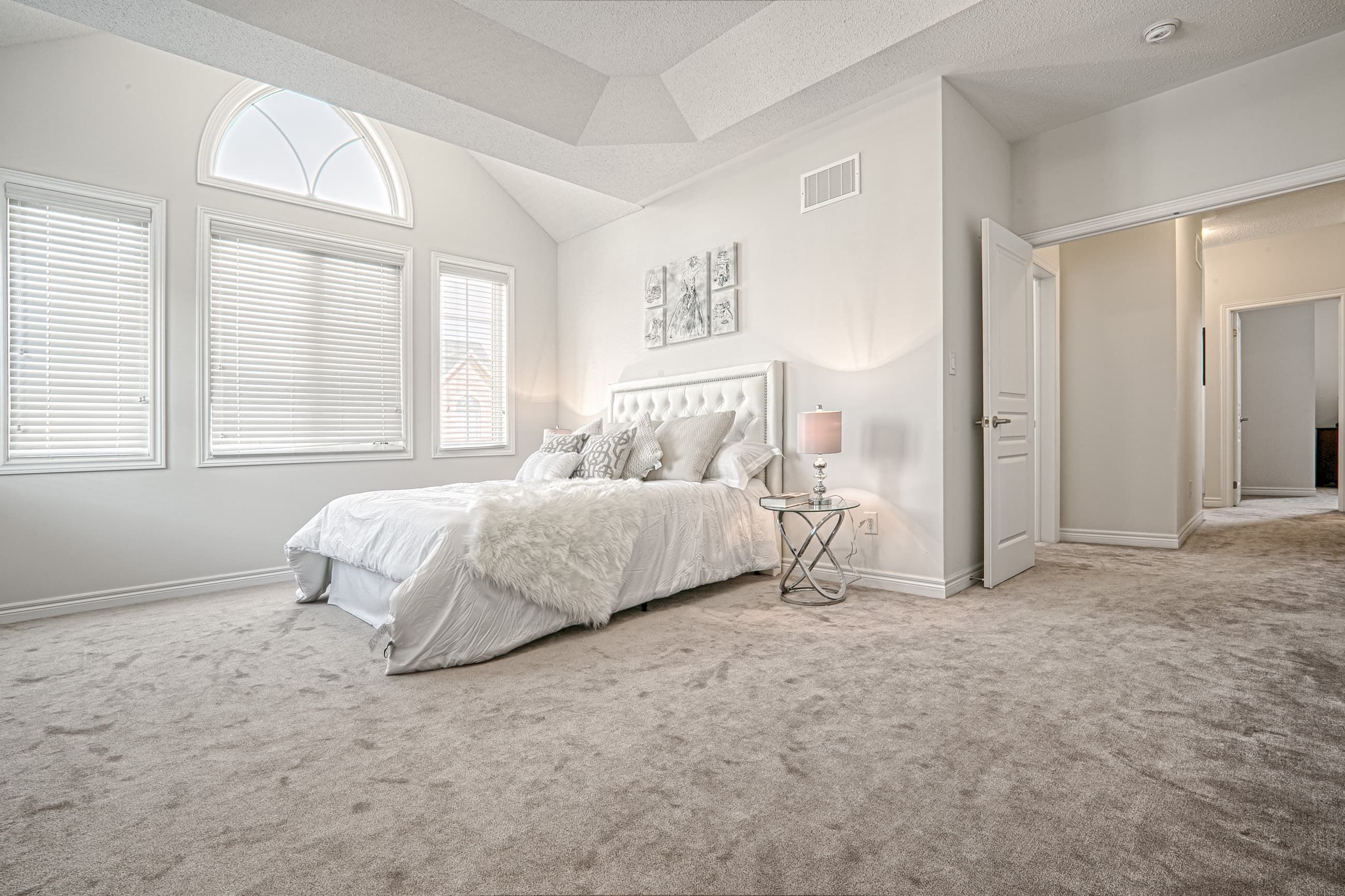 This Toronto luxury master bedroom renovation features a spacious layout with high ceilings, large arched windows, and soft neutral finishes that create a bright and relaxing atmosphere. The design includes premium carpeting, elegant lighting fixtures, and a functional layout that enhances comfort and everyday living. Completed by a professional Toronto renovation company, this bedroom interior project showcases quality craftsmanship, modern design, and timeless residential elegance tailored for contemporary homes.