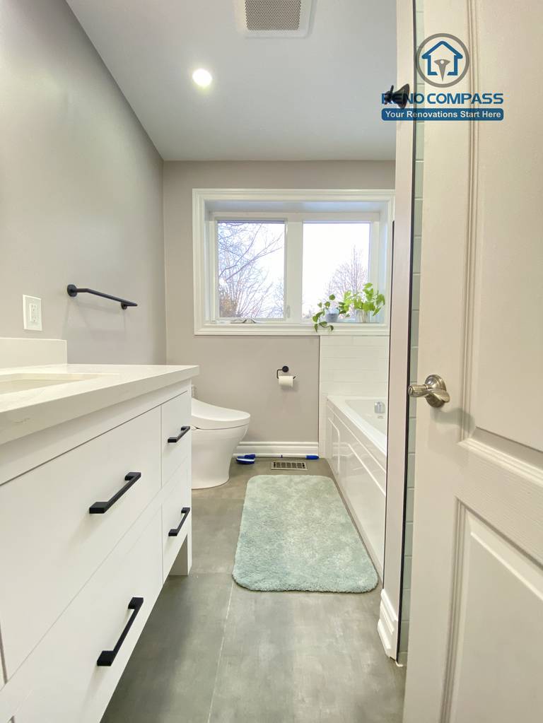 This North York bathroom renovation features a modern white vanity with a quartz countertop, matte black hardware, and a clean, functional layout. The neutral wall color, large-format floor tiles, and integrated lighting create a bright and timeless bathroom design, completed by a Toronto renovation company focused on quality craftsmanship and everyday usability.